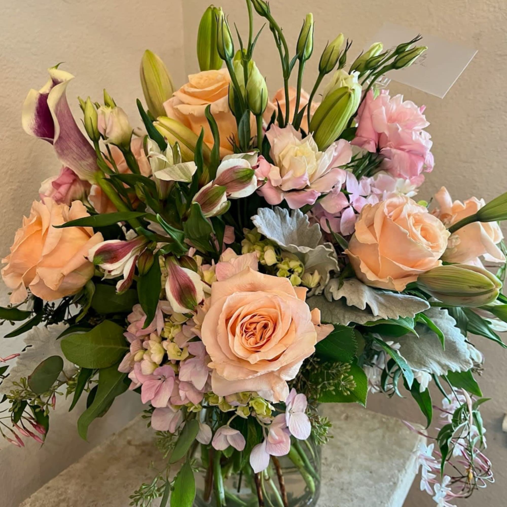Peach roses and pink lilies arranged in a glass vase