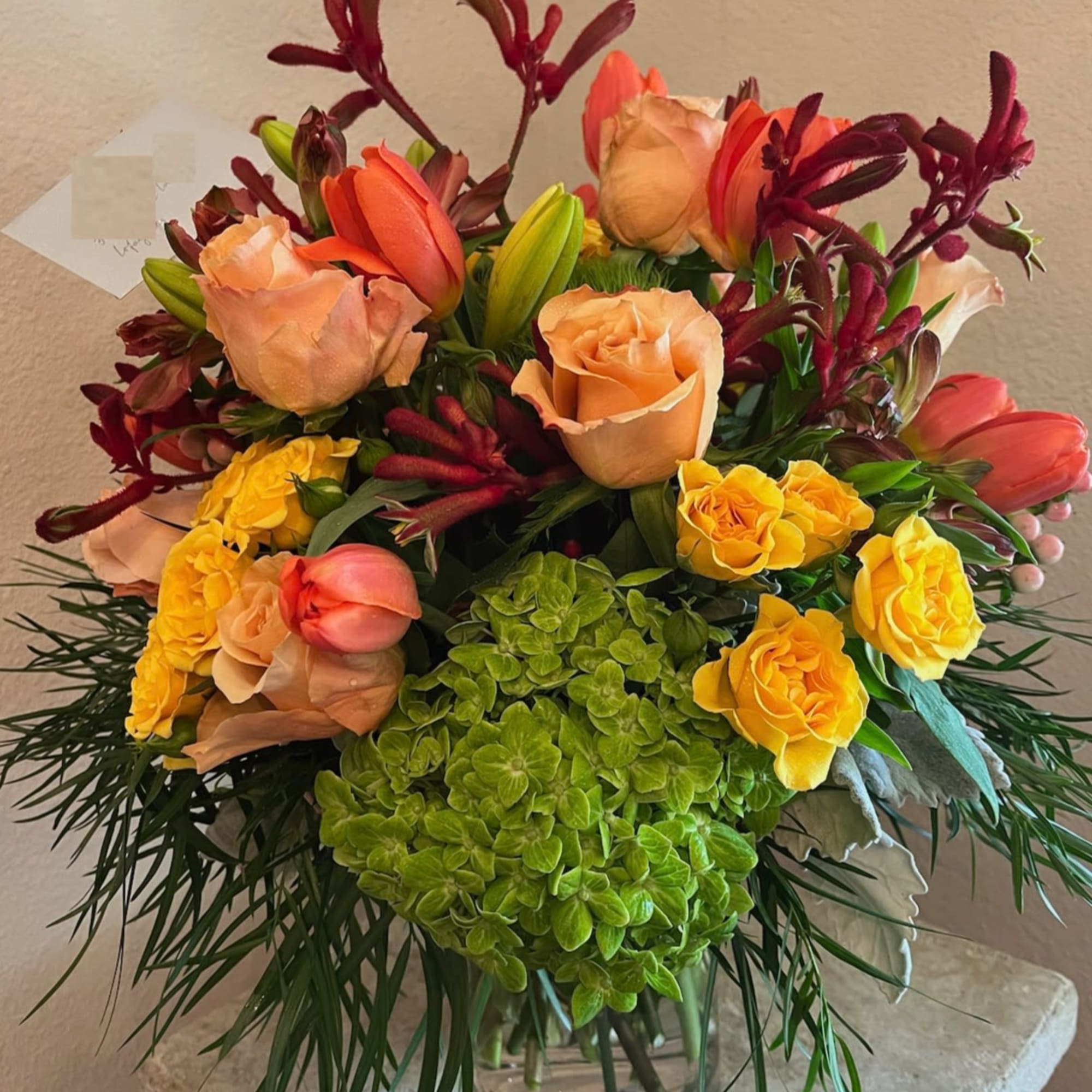 Mixed bouquet of roses, tulips, and hydrangea in a glass vase