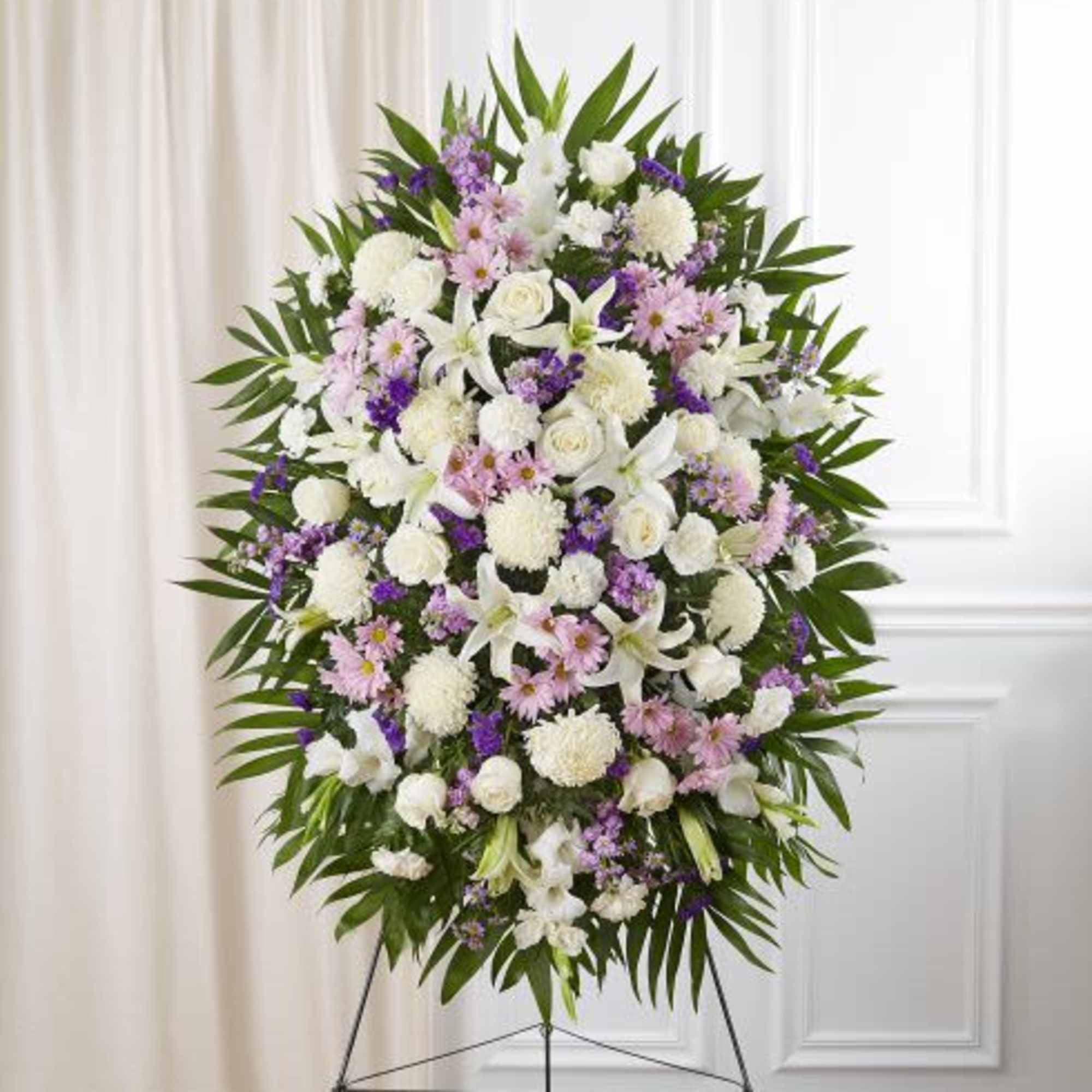 Standing spray of white, pink, and purple flowers with greenery on an easel