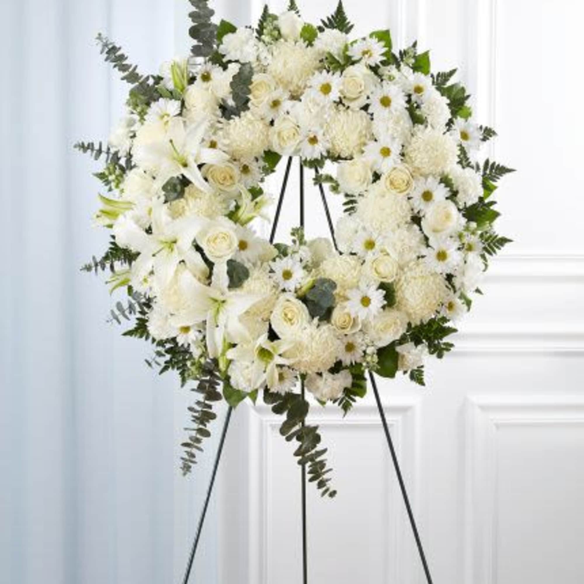 Standing white floral wreath with roses, lilies and mums on a metal easel