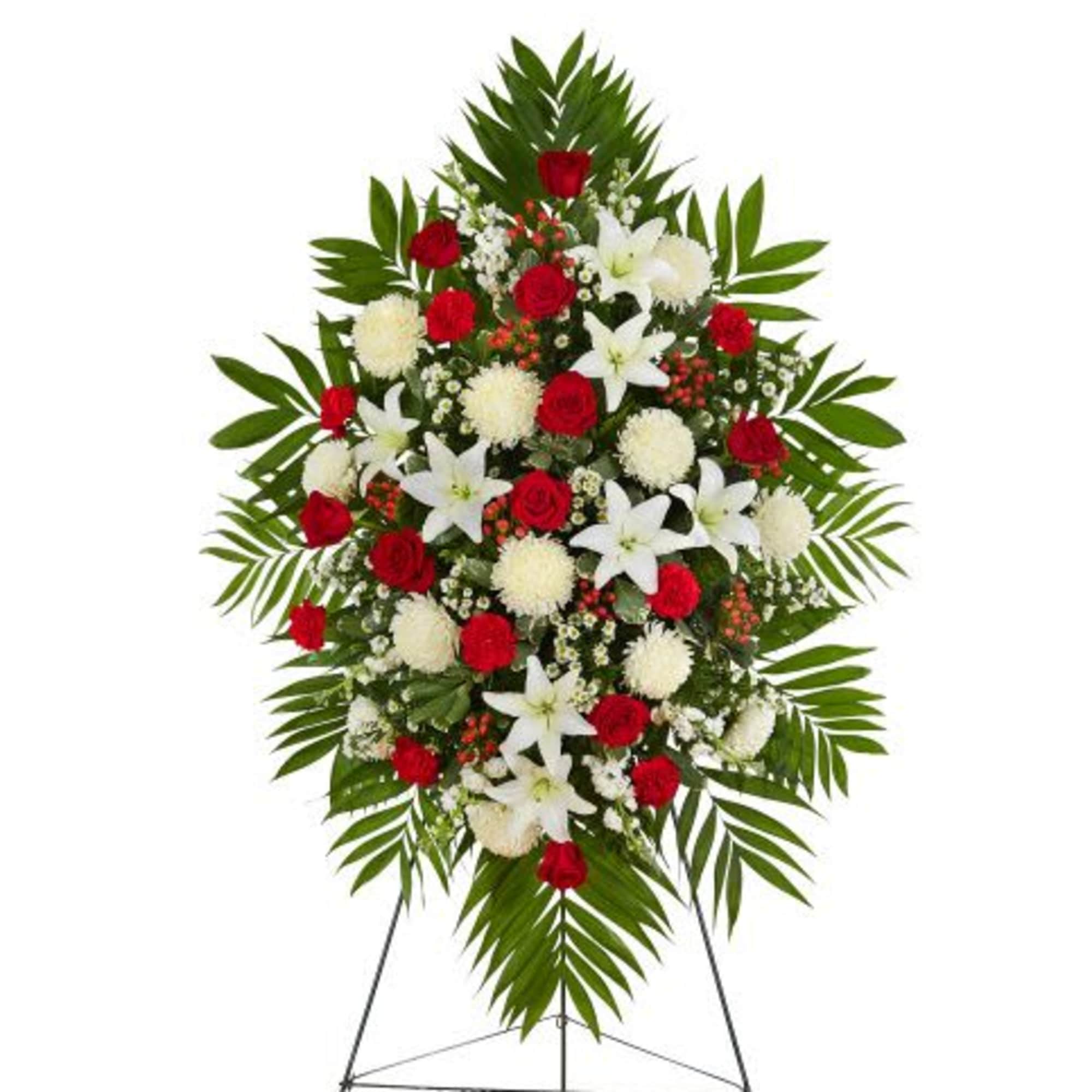 Standing spray of red roses, white lilies, and white mums with large palm fronds on an easel