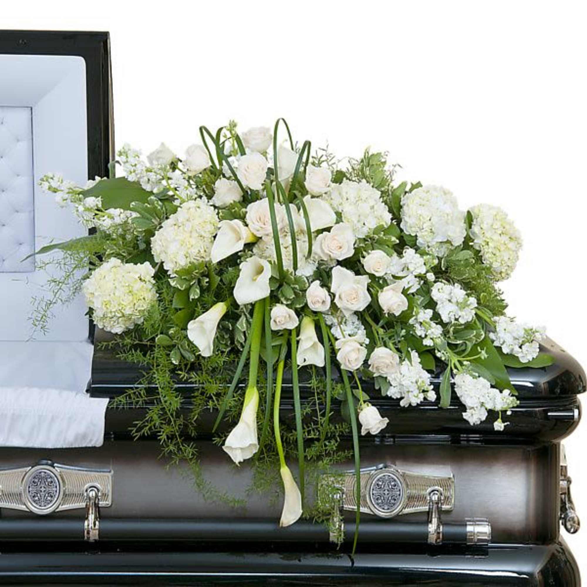 White casket spray of roses, calla lilies, and hydrangeas on a dark coffin