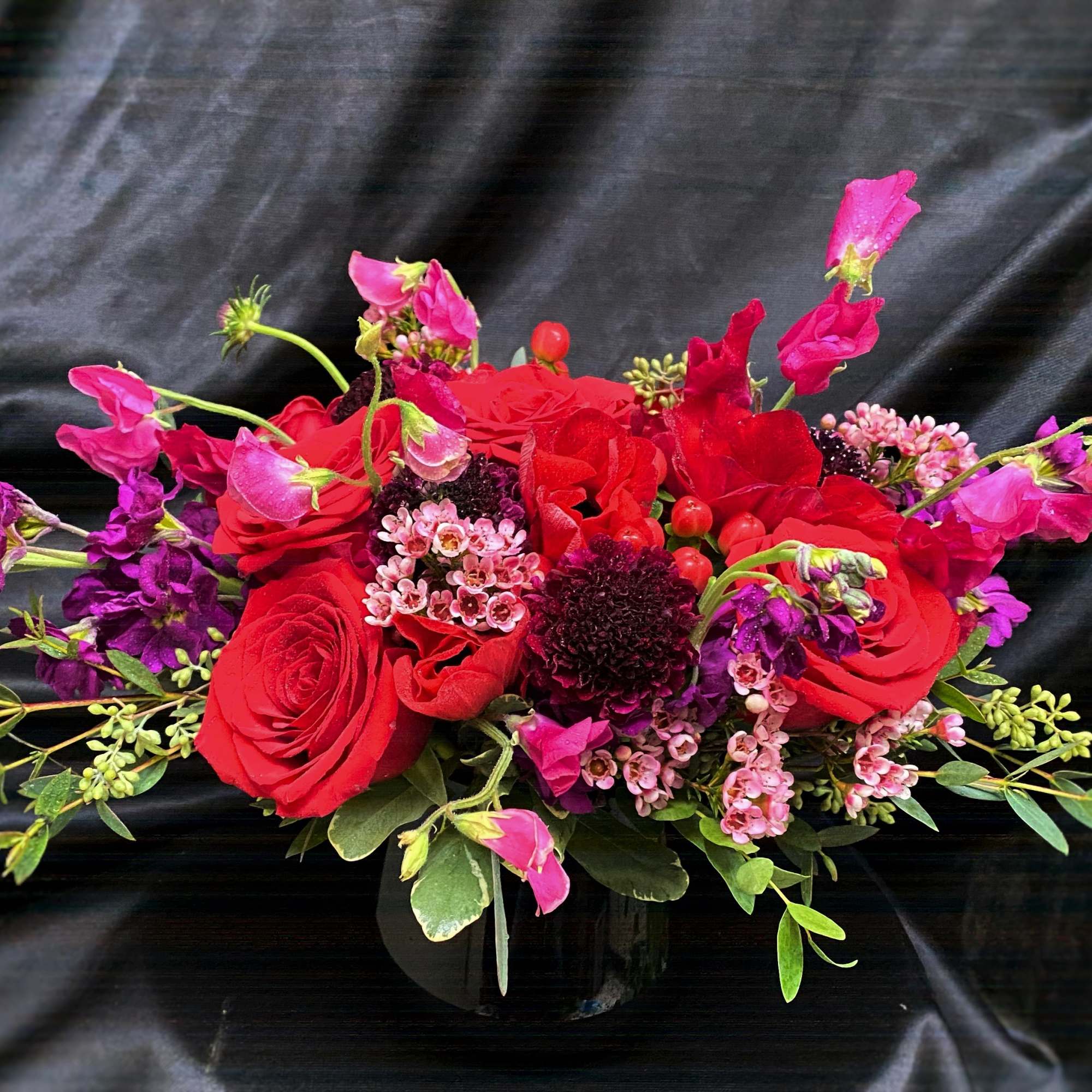 Red and pink mixed flower arrangement in a black vase