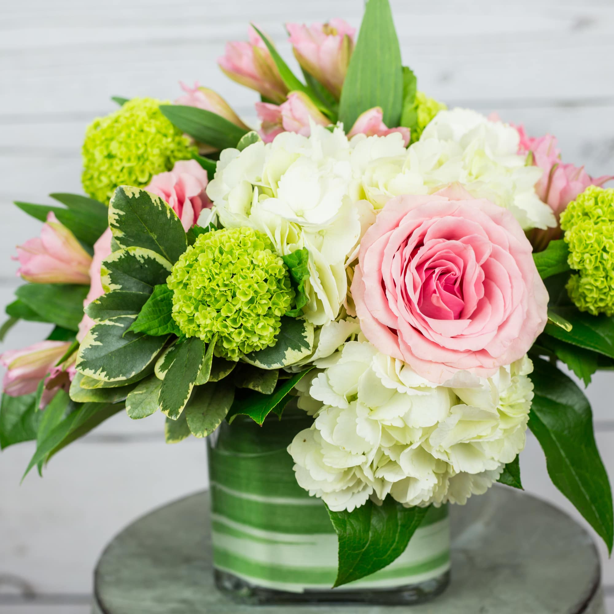 Pink roses and white hydrangeas in a glass vase with green blooms