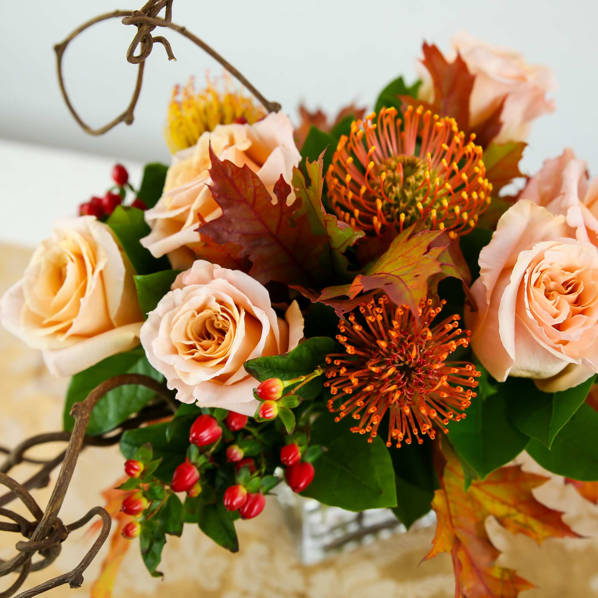 Peach roses and orange pincushion flowers in a hanging basket