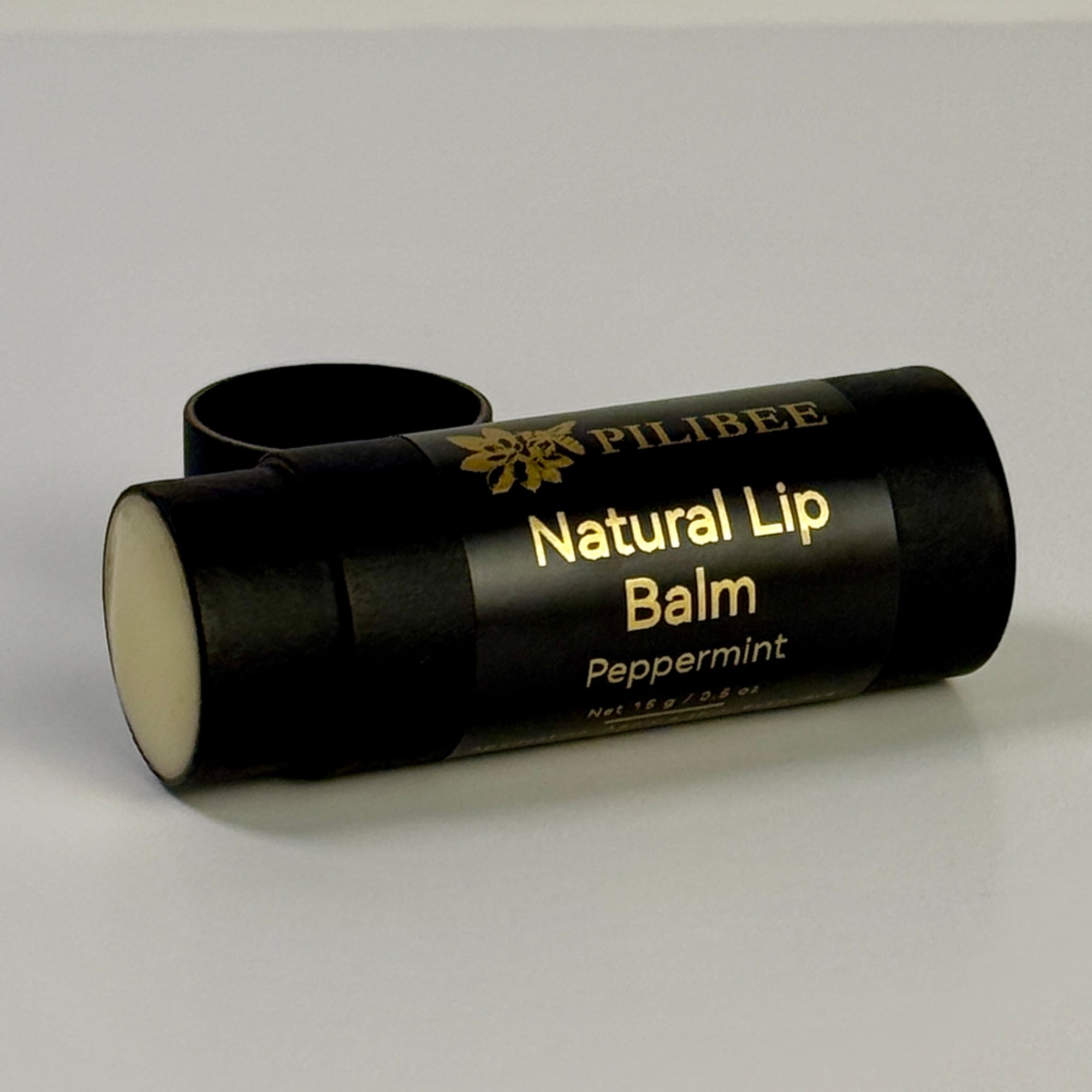 Black lip balm tube labeled Peppermint on a white surface