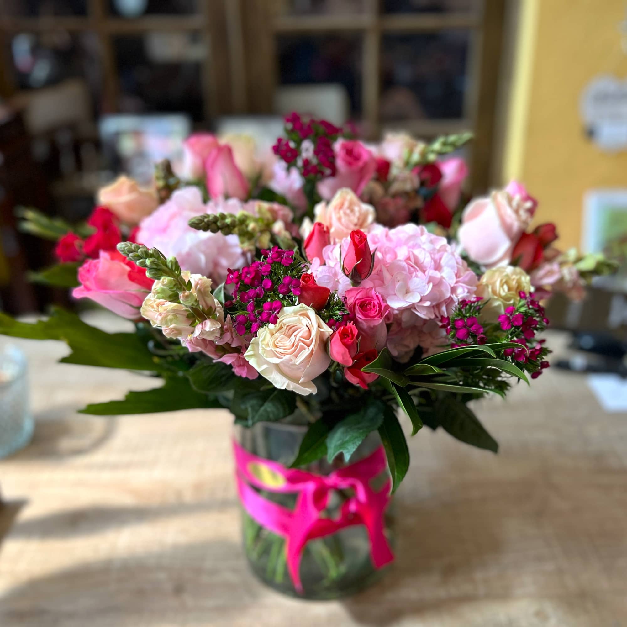 Pink and cream bouquet in a glass vase with a bright ribbon