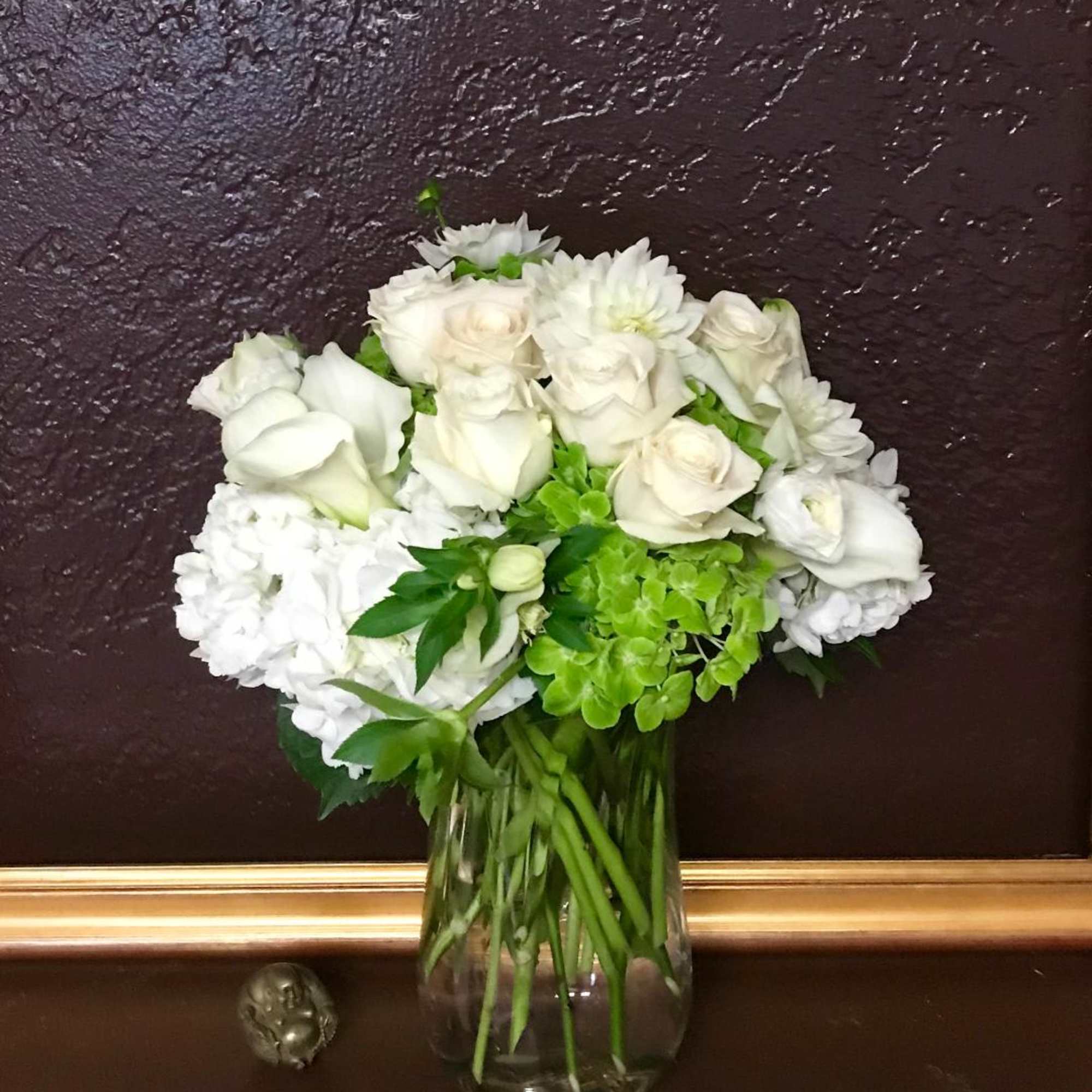 White roses and hydrangeas arranged in a clear glass vase