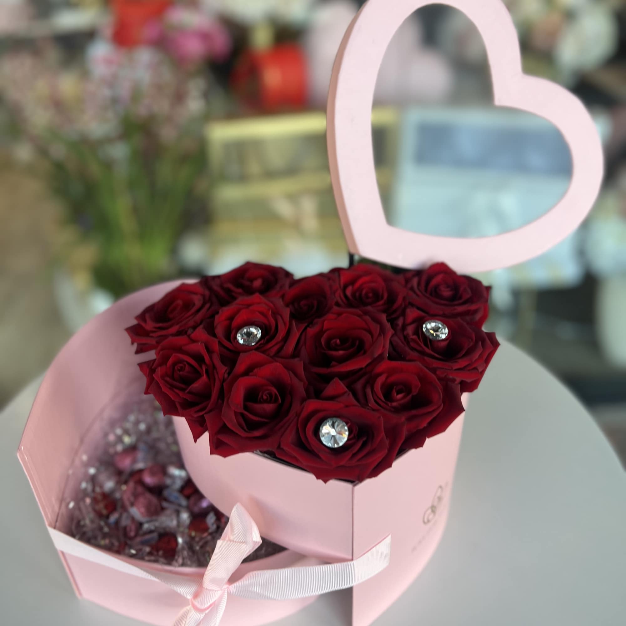 Pink heart-shaped box with red roses and a matching heart topper