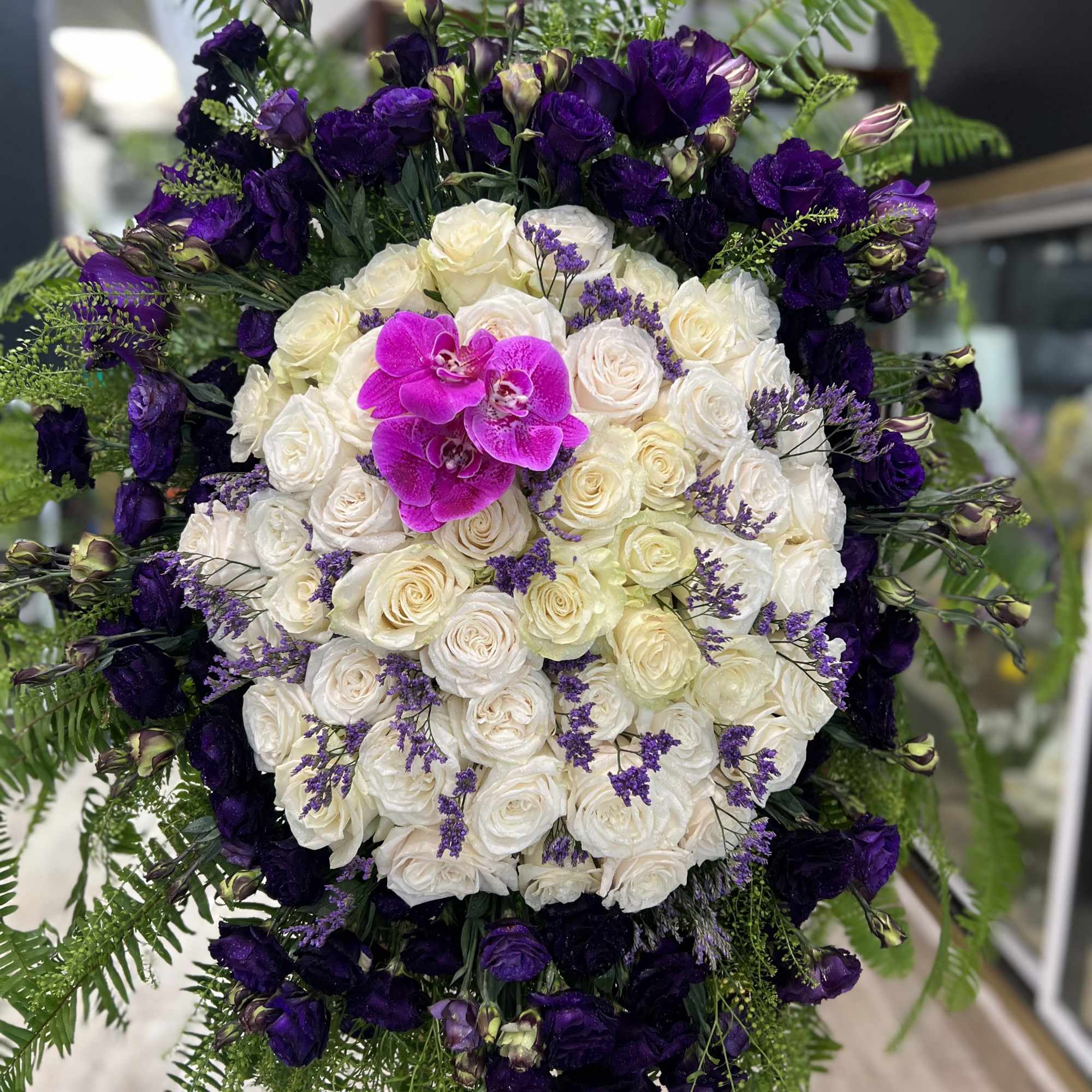 Large bouquet of white and purple roses with a bright pink orchid center