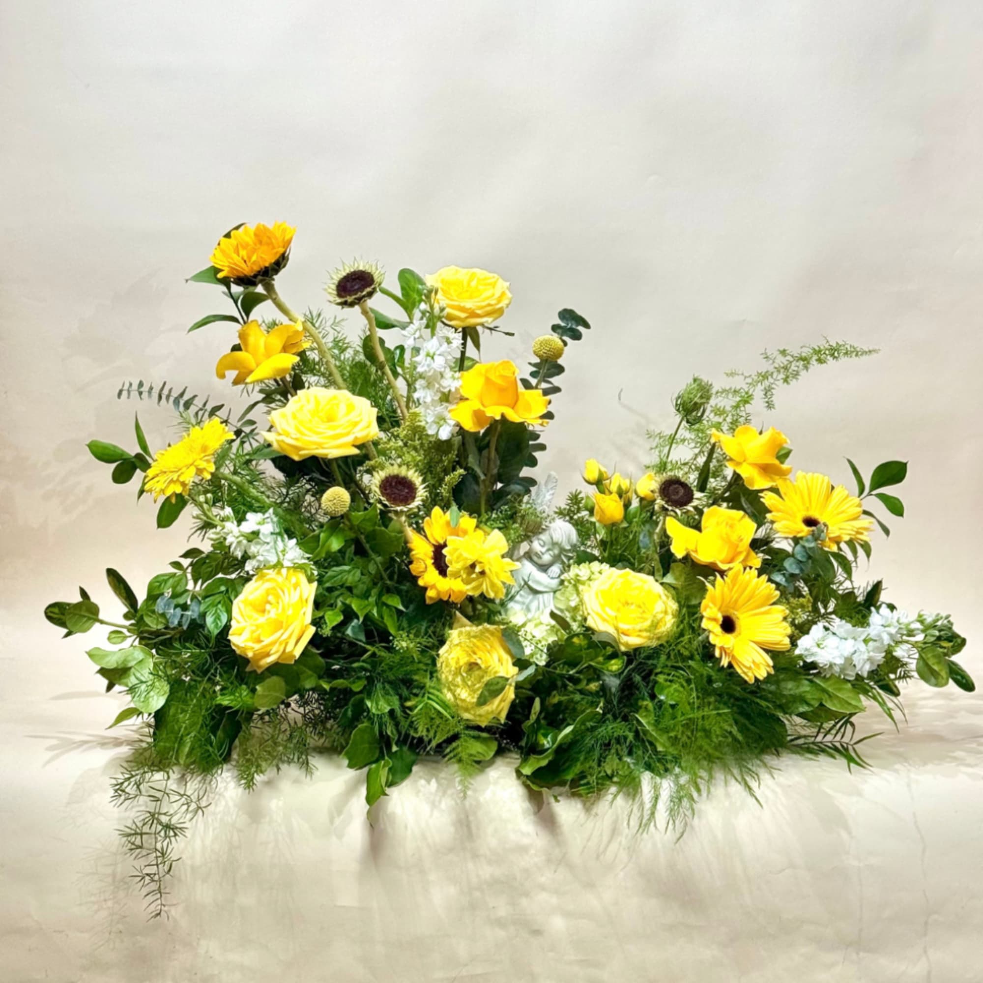 Yellow roses and daisies arranged in a low, wide floral display