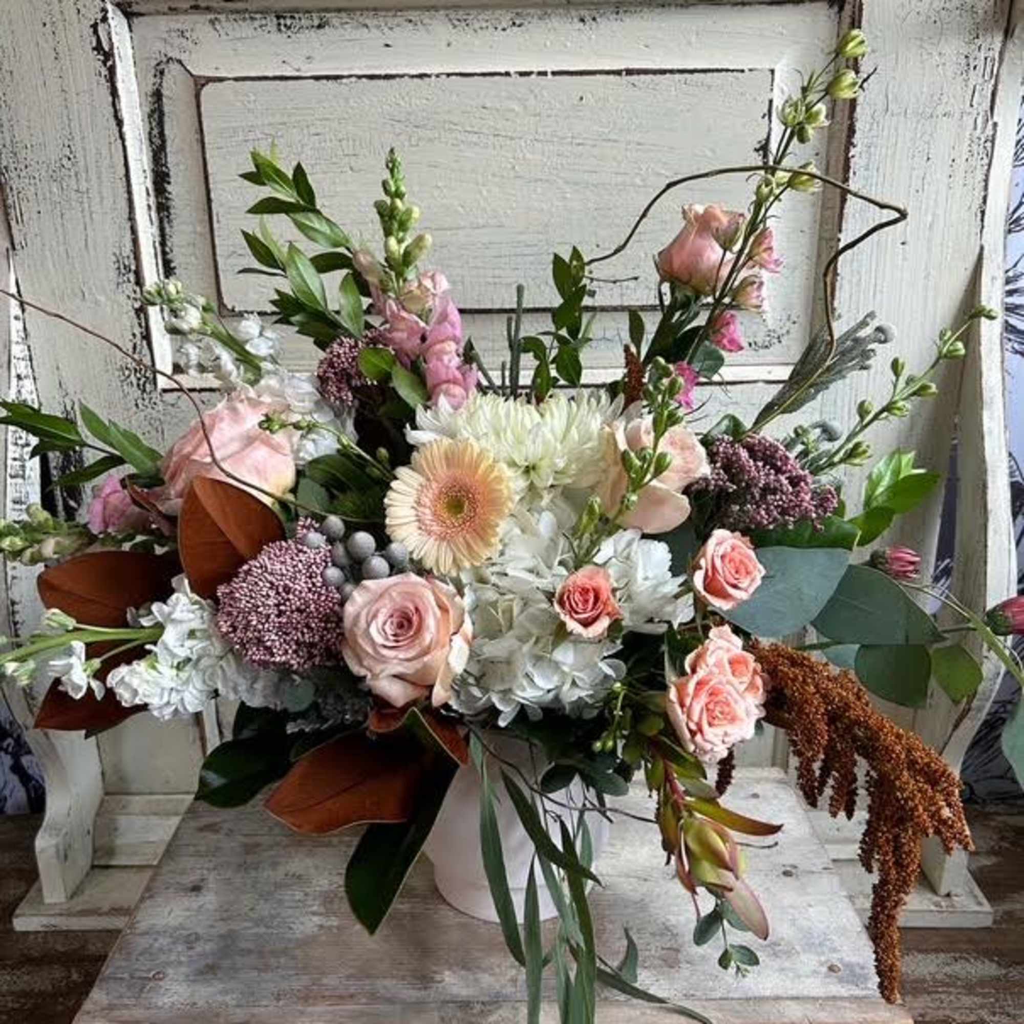 Large mixed bouquet with pink roses, white blooms, and greenery in a white container