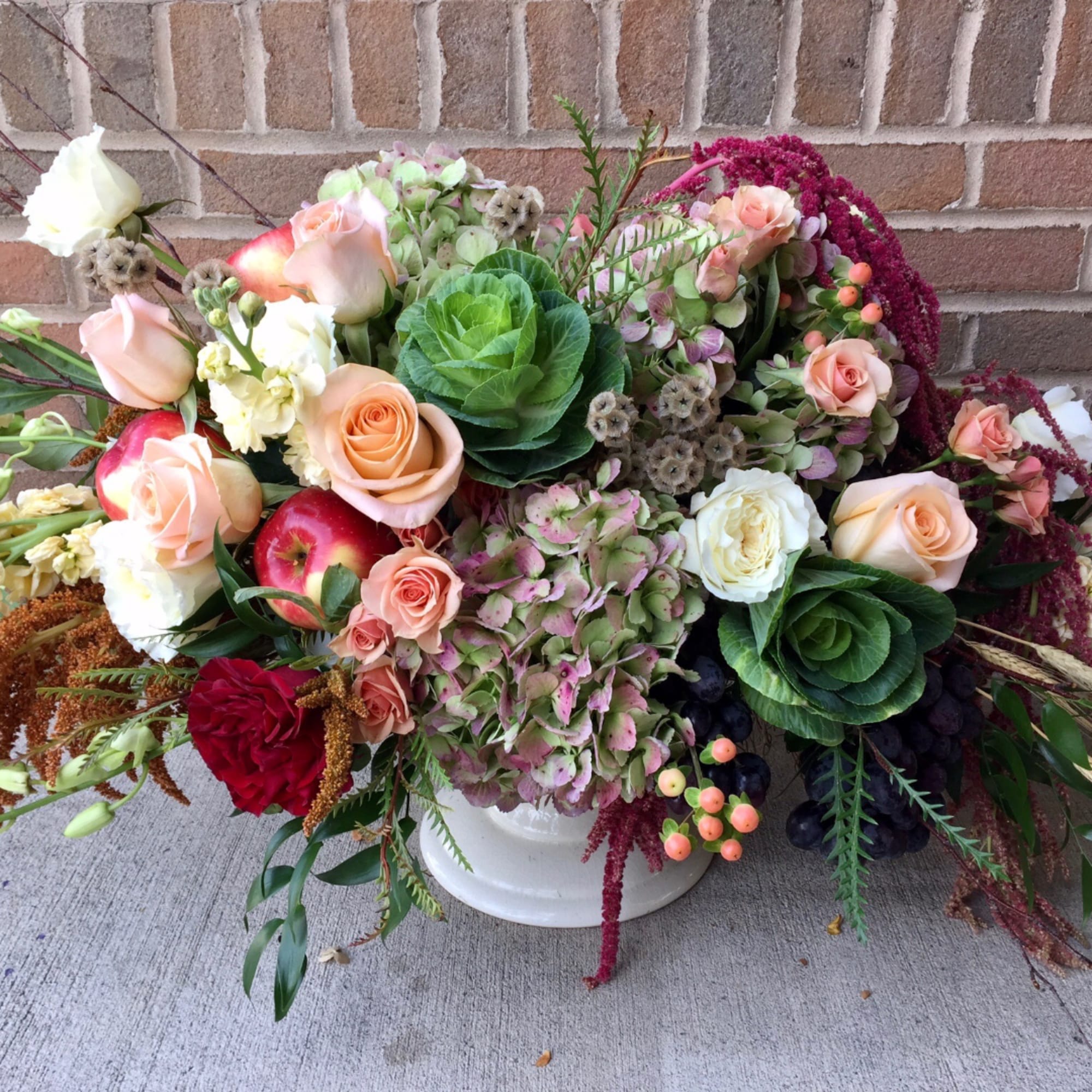 Mixed bouquet of roses, hydrangeas, and greenery in a white vase
