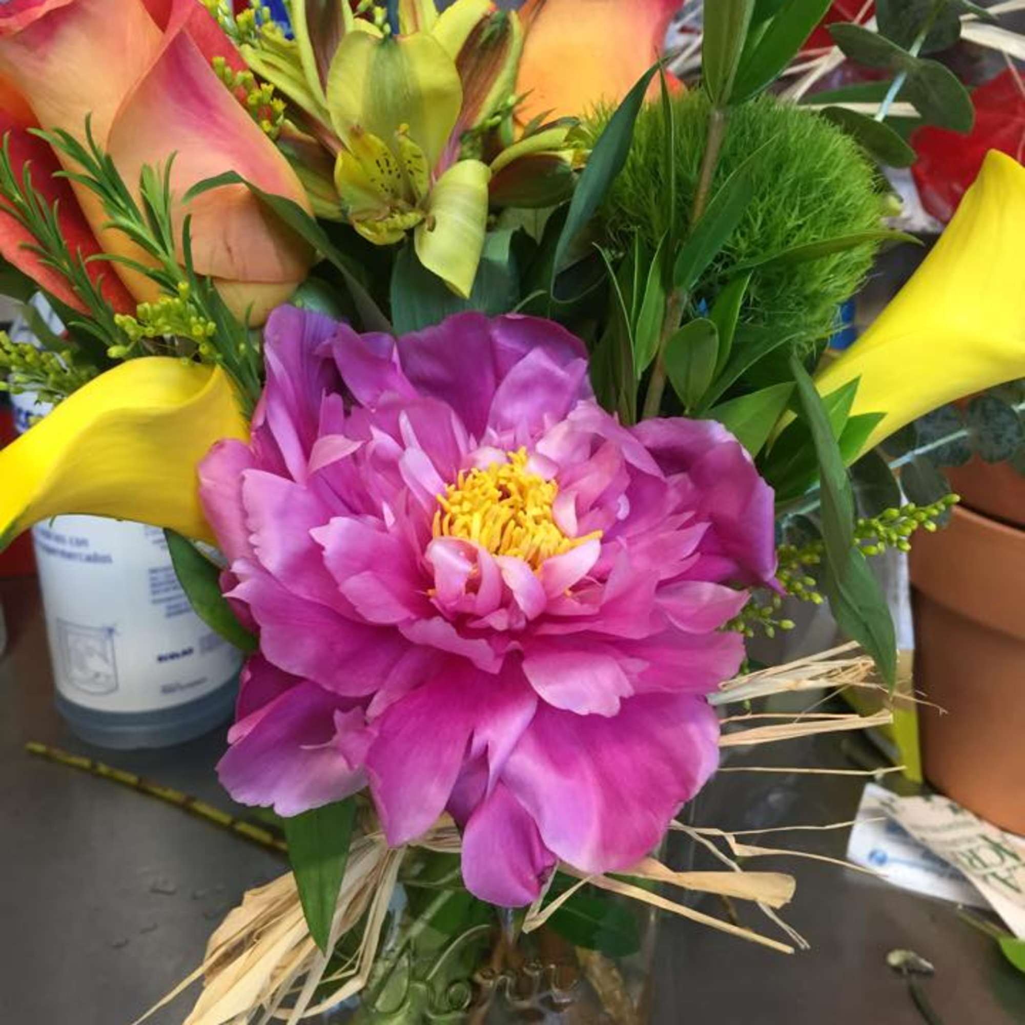 Bouquet with pink peony, yellow calla lilies, and orange roses in a glass jar
