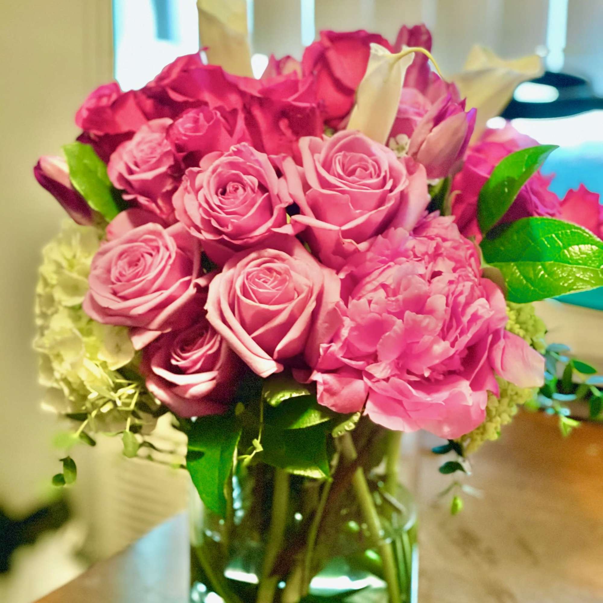 Pink and magenta roses arranged in a clear glass vase