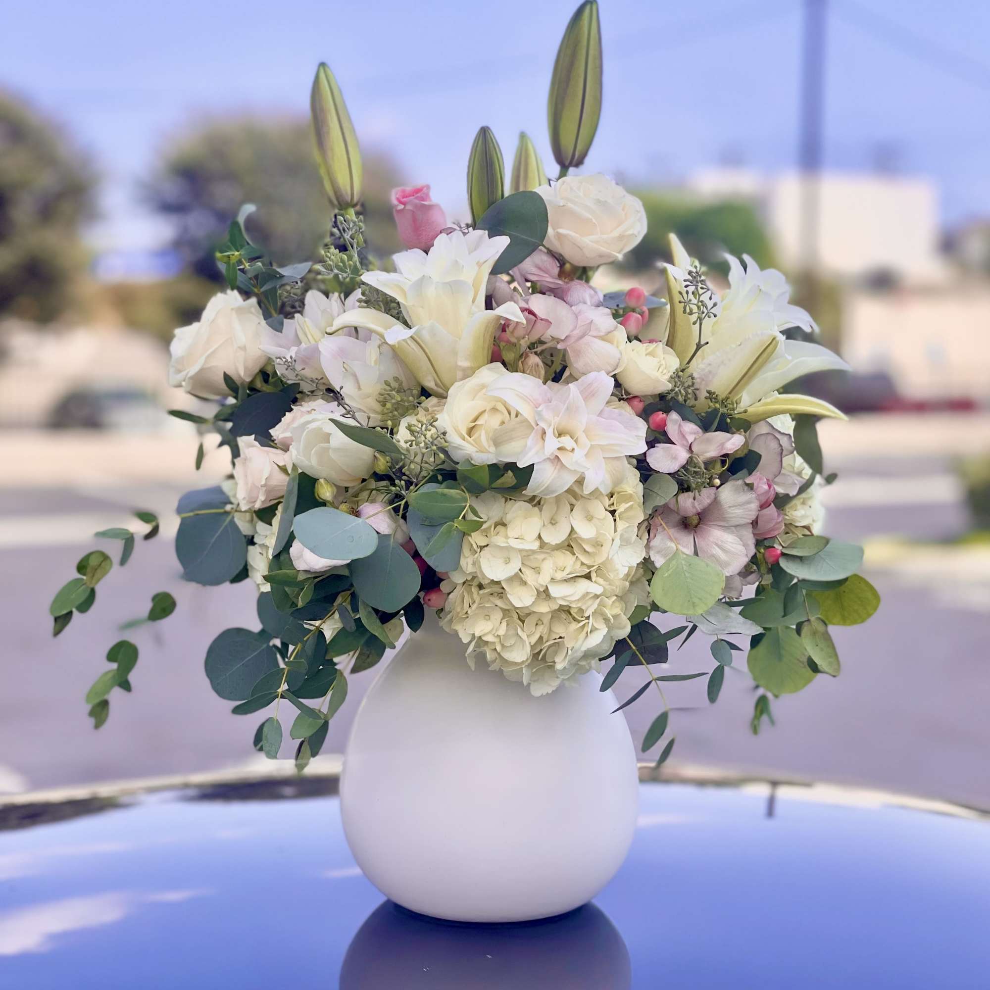 White and blush floral arrangement in a round white vase