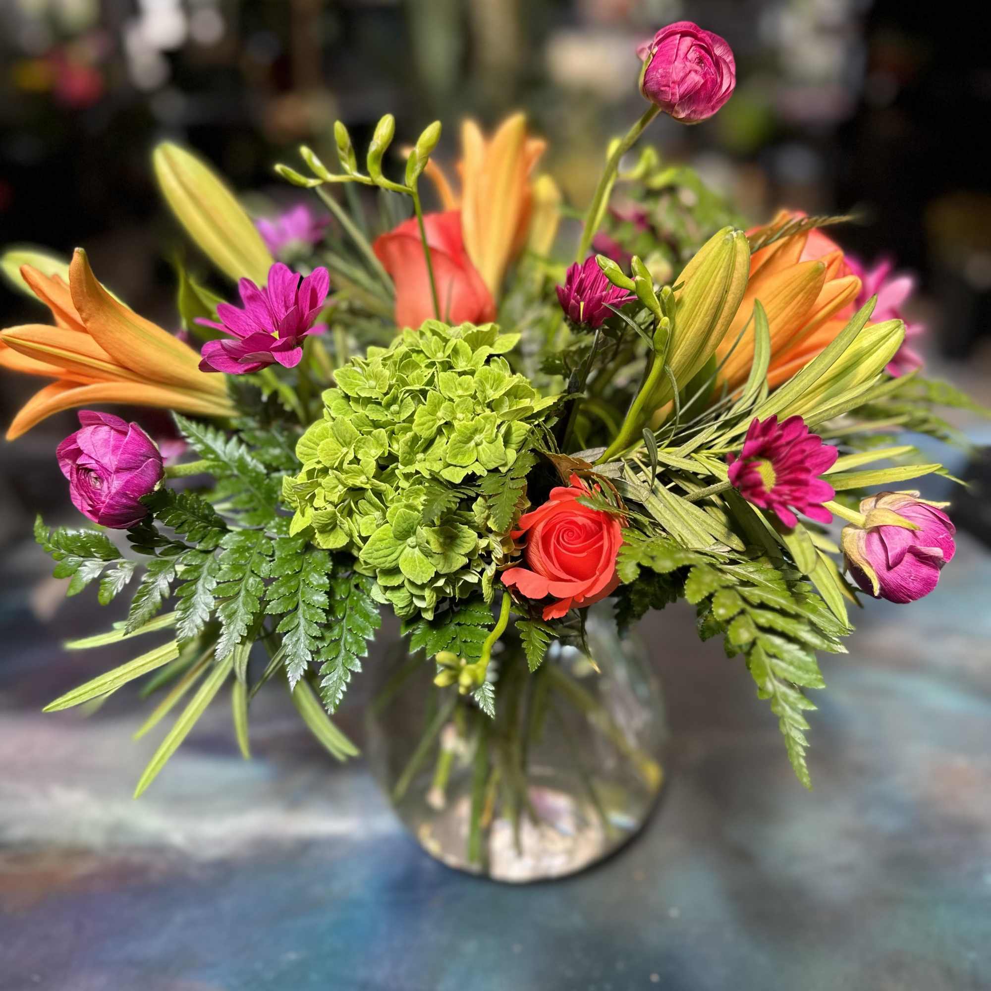 Designed using orange asiatic lilies, green hydrangeas, coral charm roses, purpely ranunculus