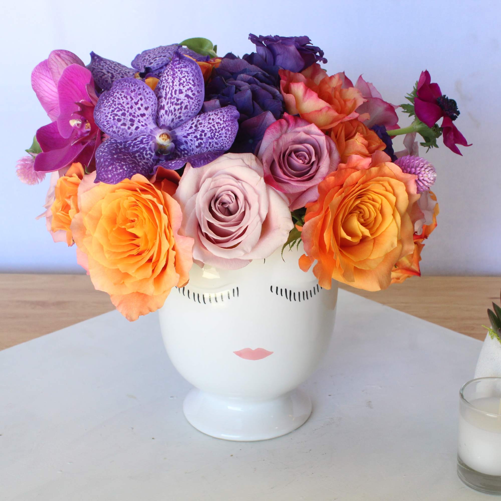 Colorful bouquet of roses and orchids in a white face vase