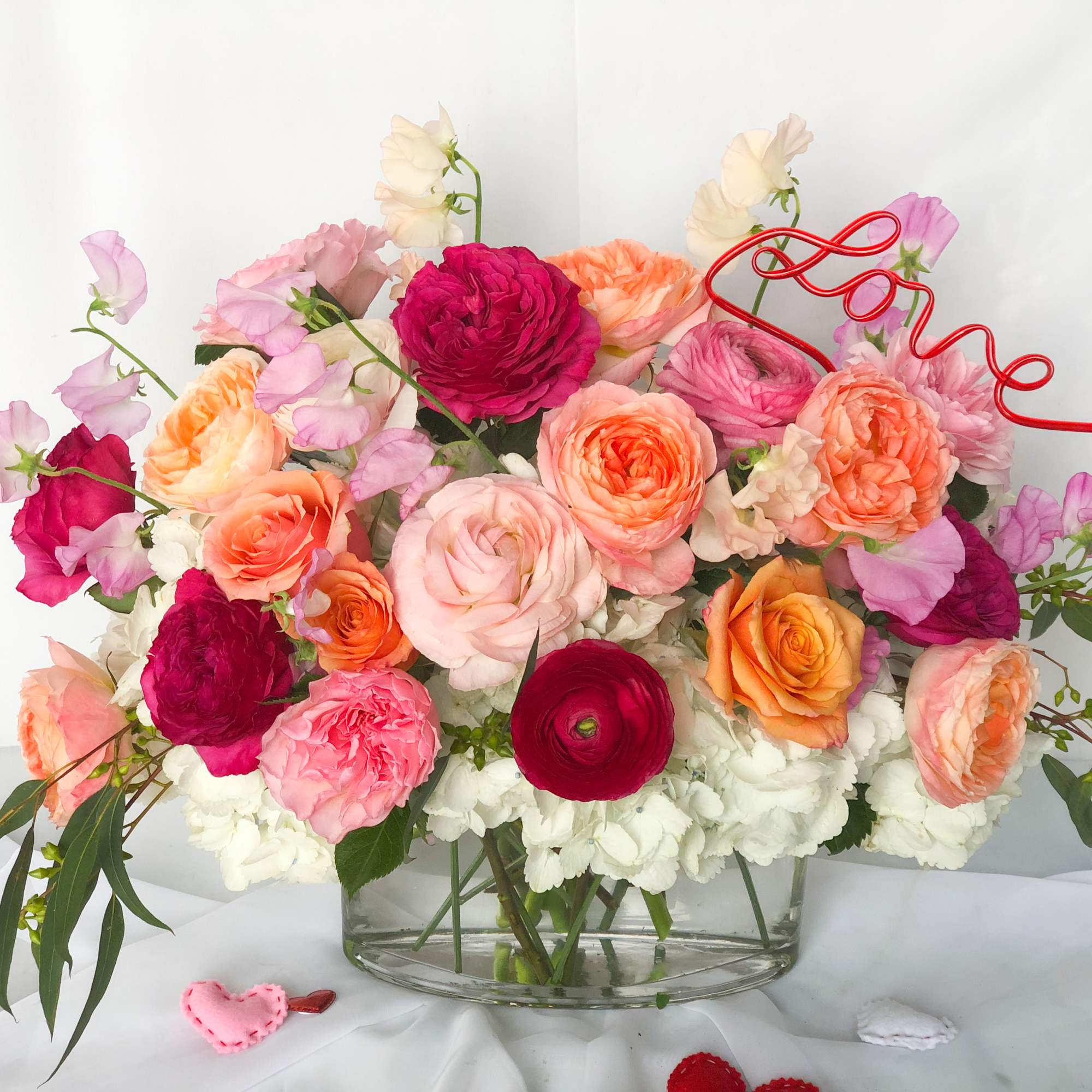 Mixed pink, peach, and white flowers in a clear glass vase