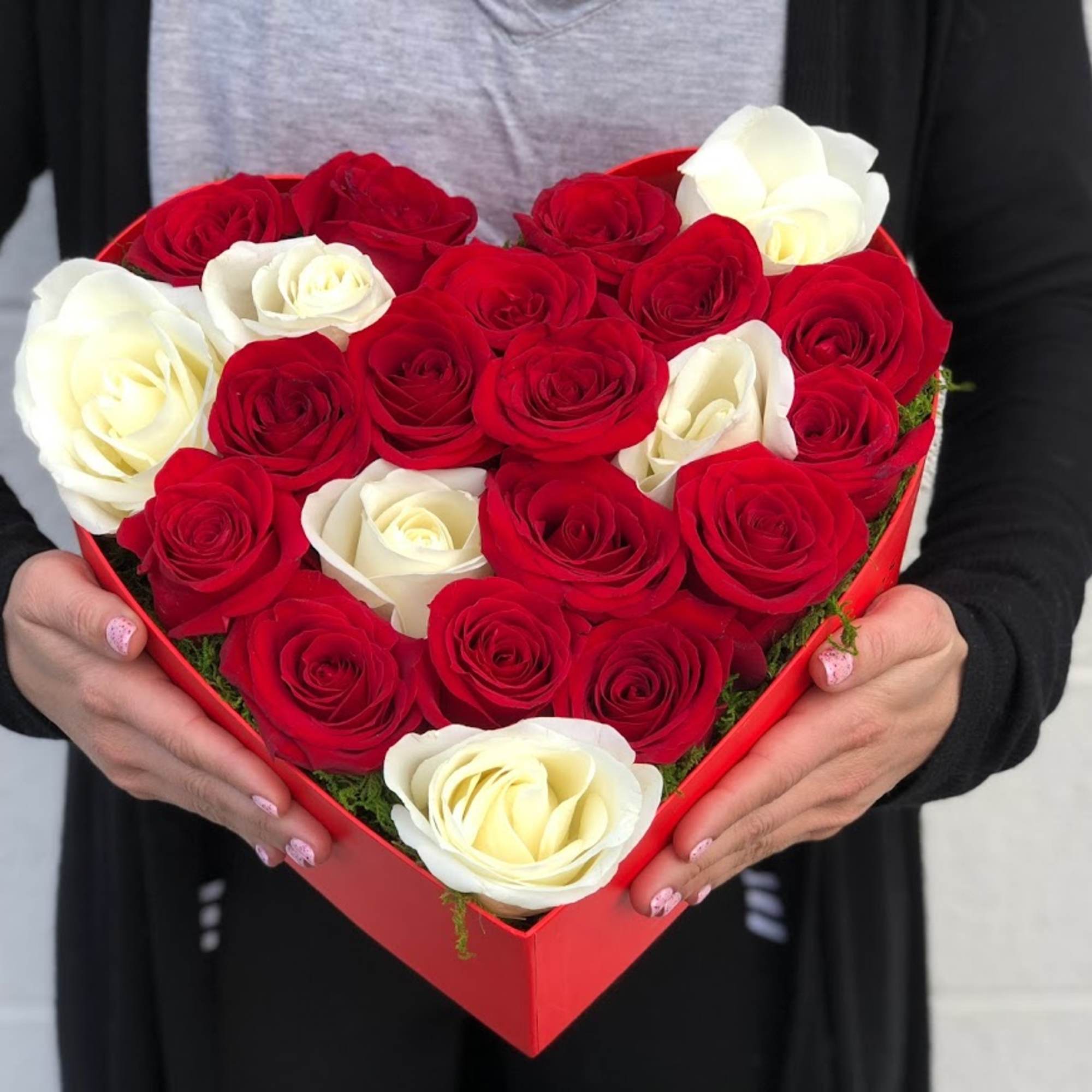 Heart-shaped box of red and white roses held in two hands
