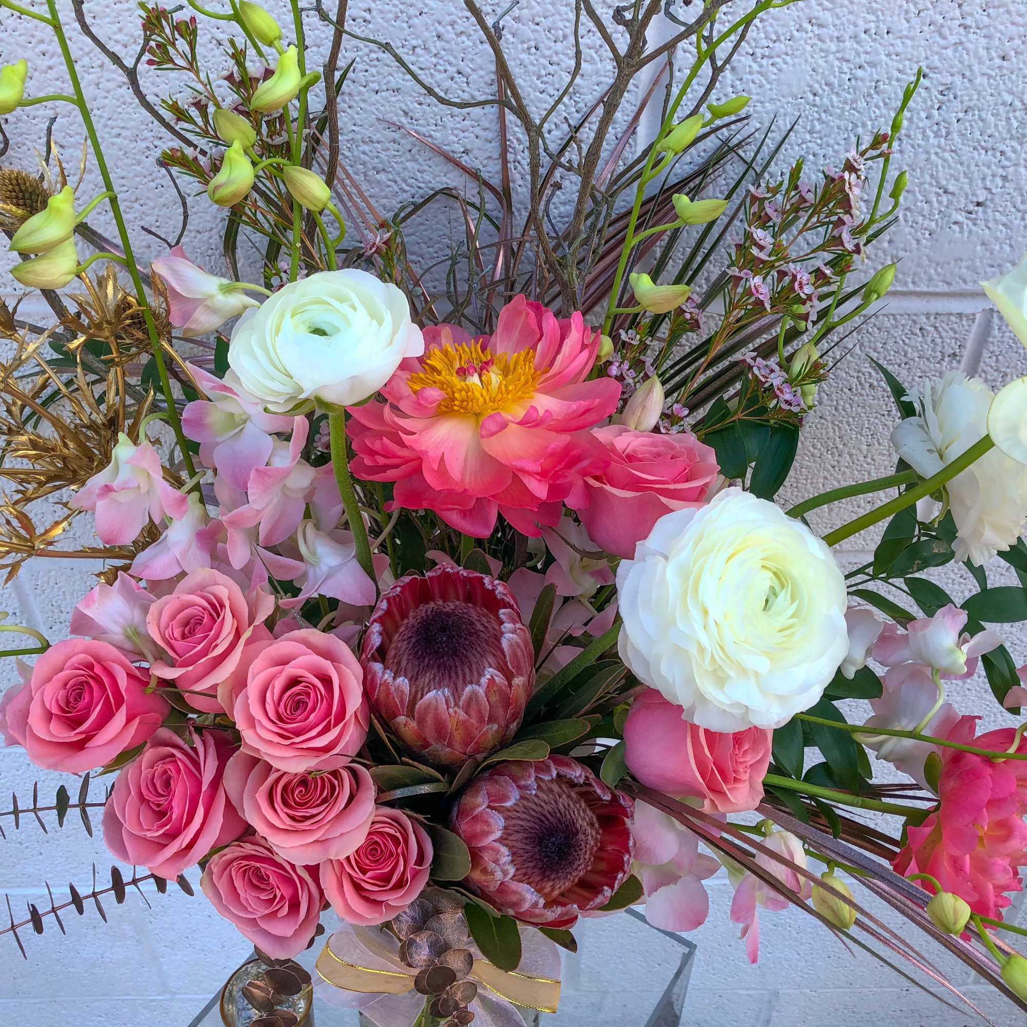 Bouquet of pink and white flowers with protea and orchids in a vase