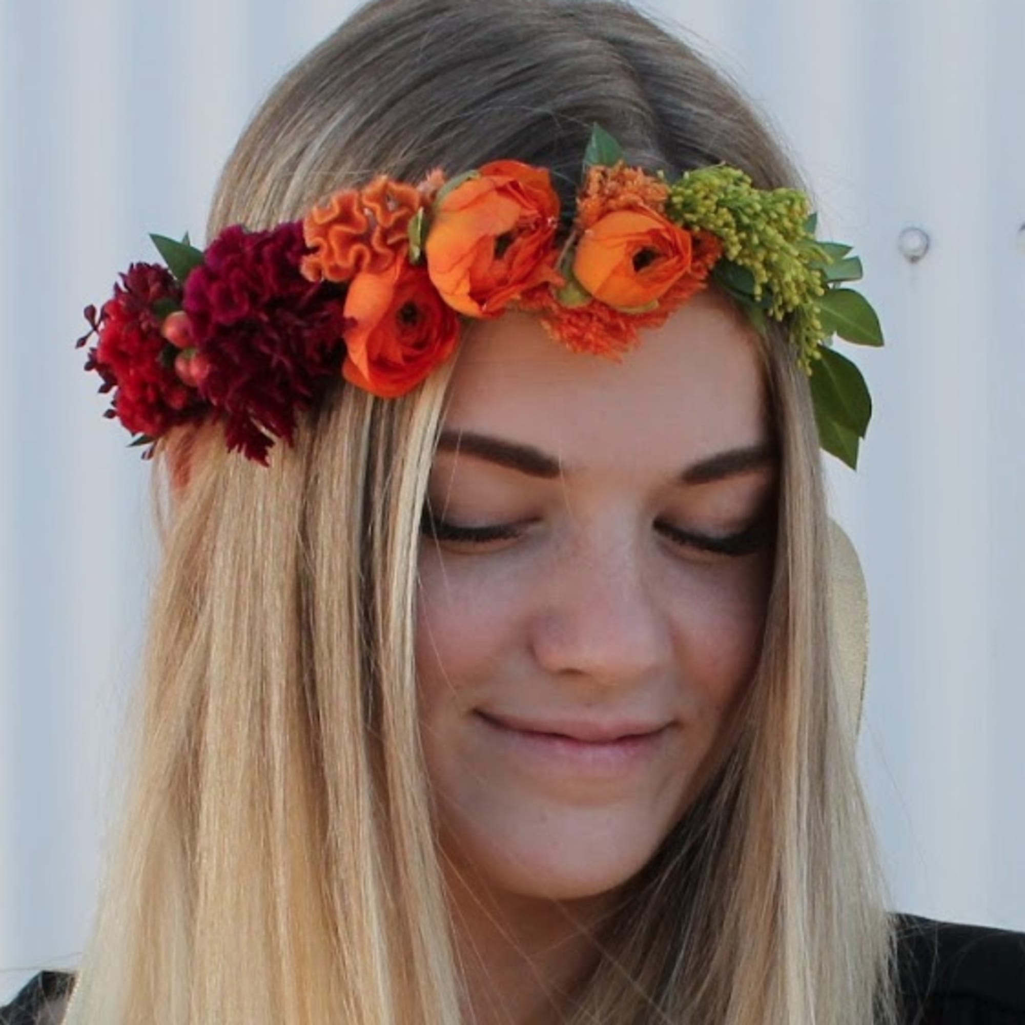 Woman wearing a flower crown with orange and red blooms