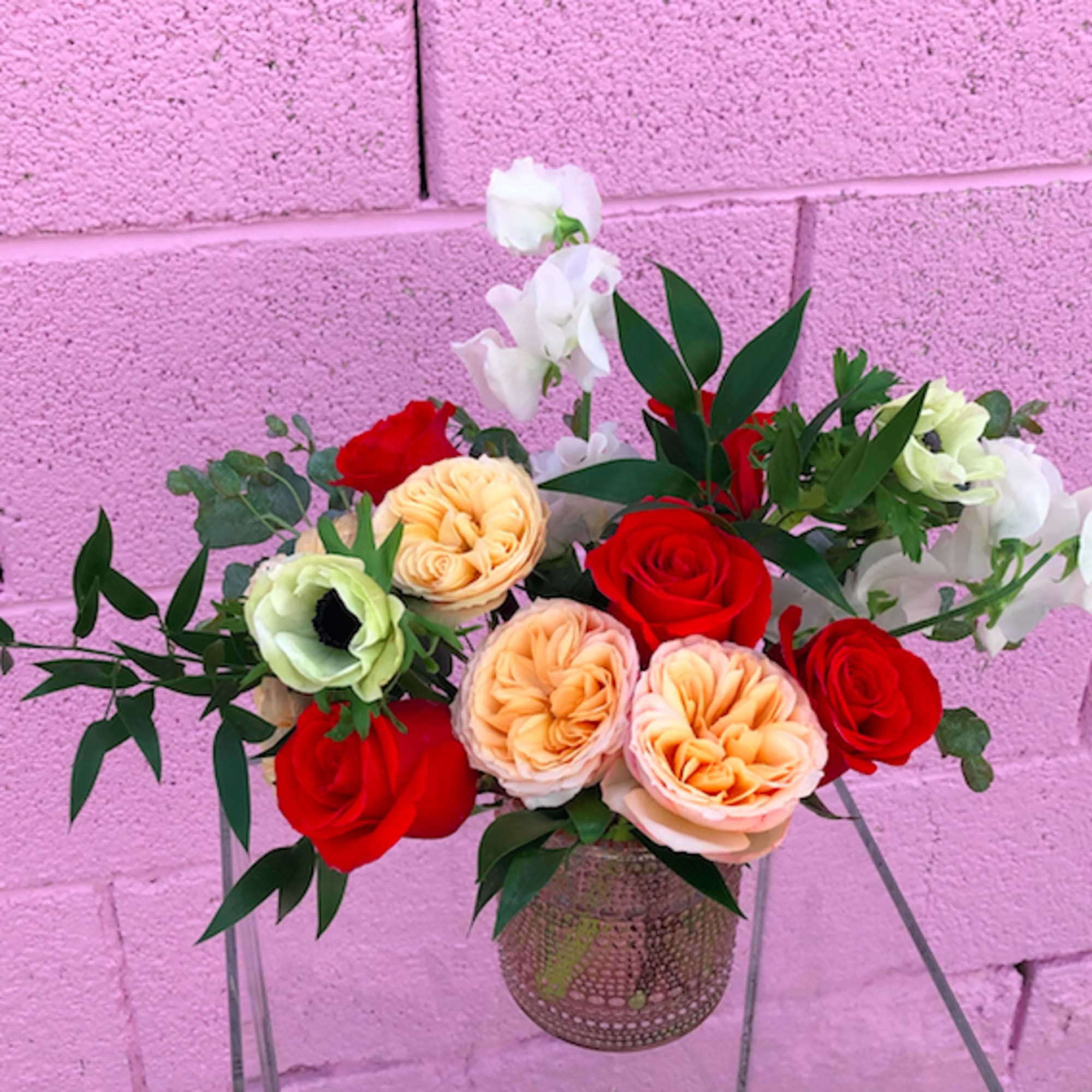 Arrangement of red, peach, and white flowers in a glass vase