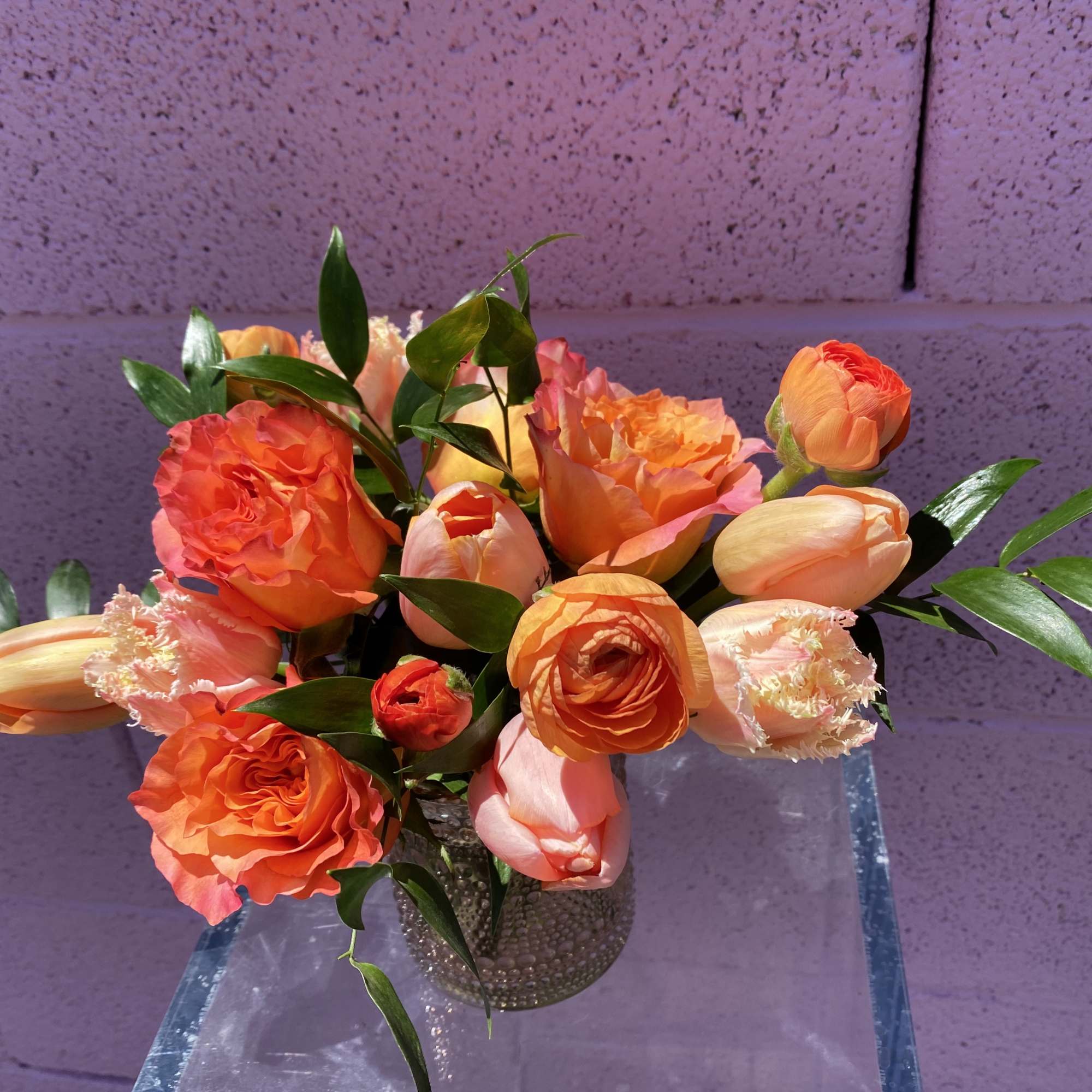 Orange and peach tulips arranged in a glass vase