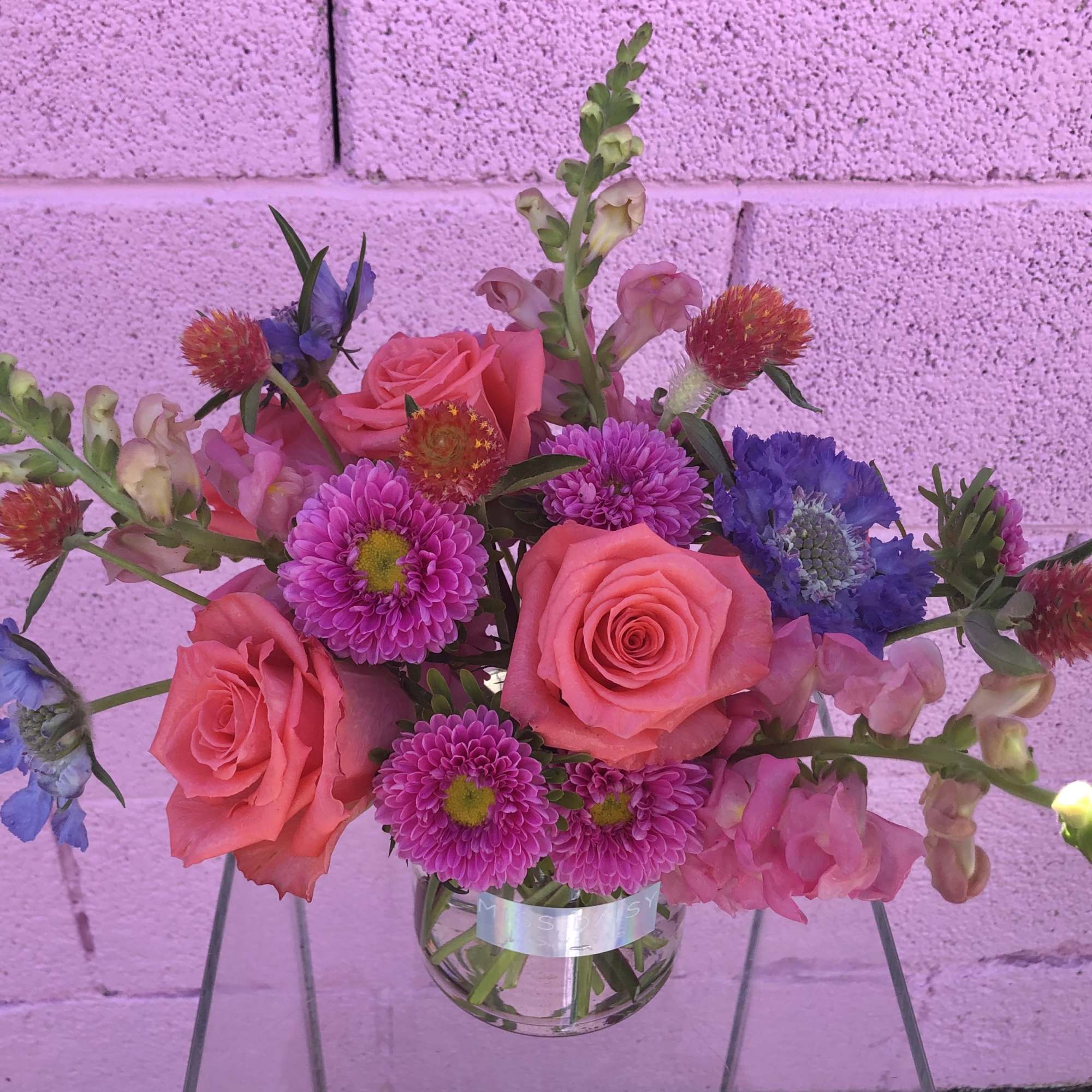 Pink roses and purple flowers in a clear glass vase