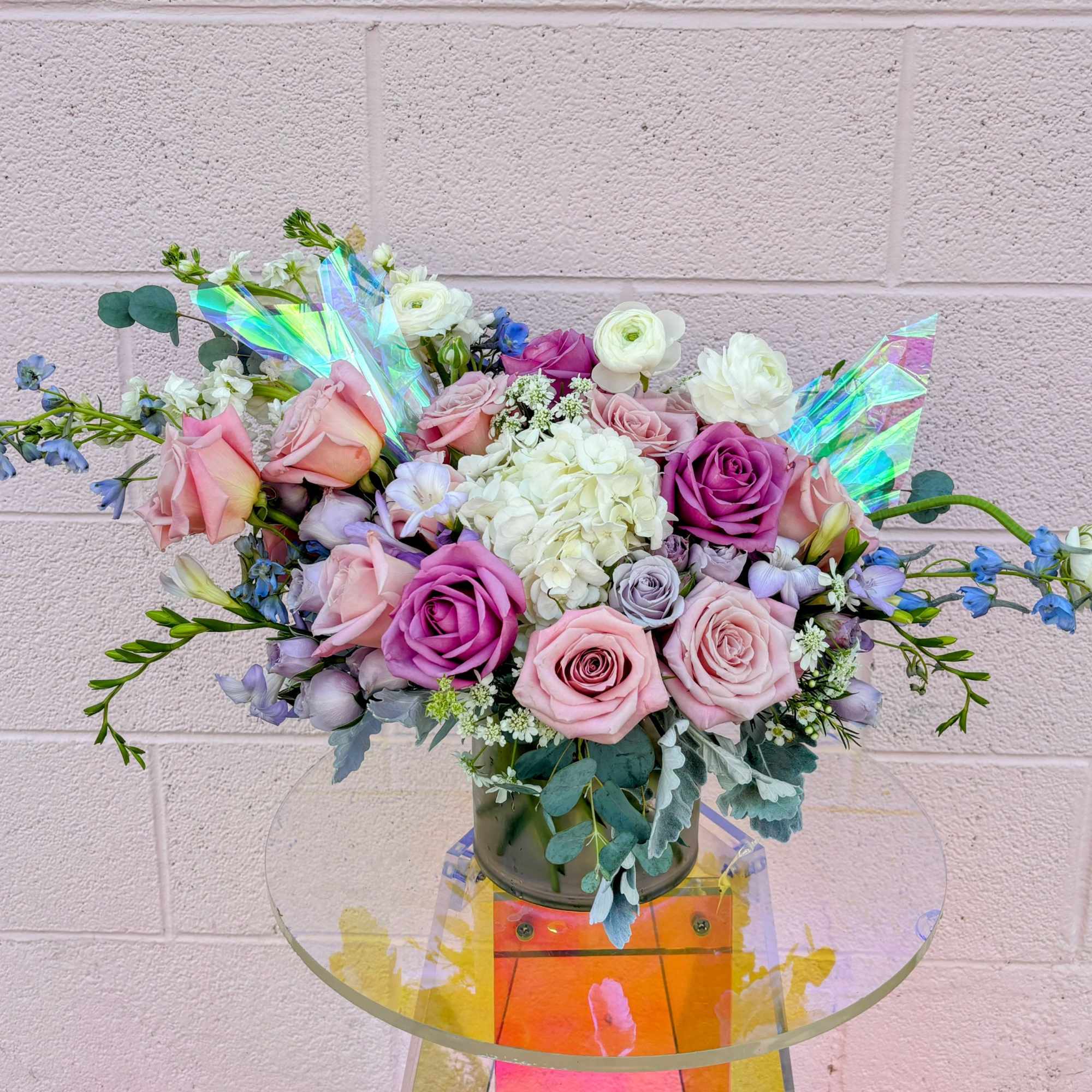Bouquet of pink and purple roses with white blooms in a glass vase