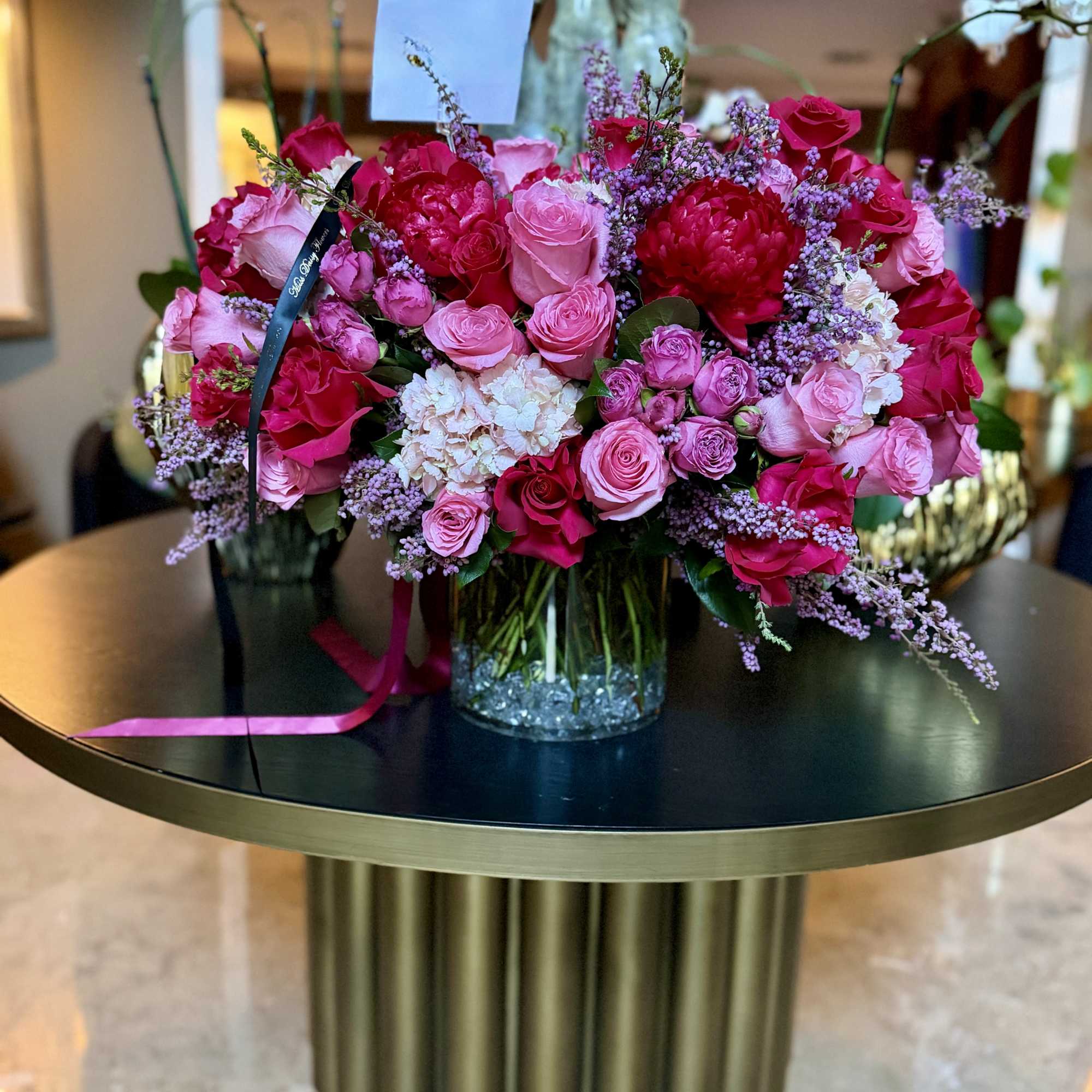 Pink and red rose arrangement in a glass vase with lavender filler