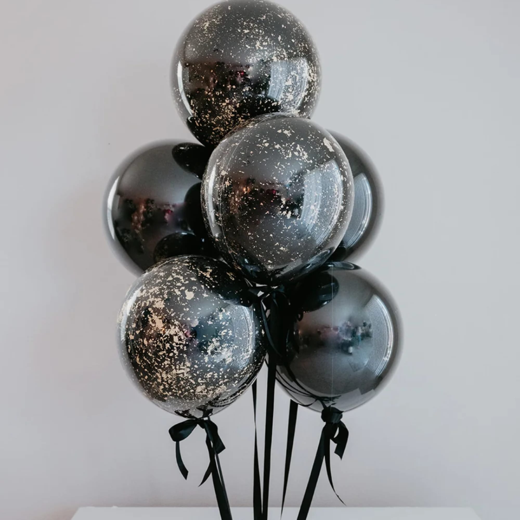 Cluster of black balloons with gold speckles and ribbons