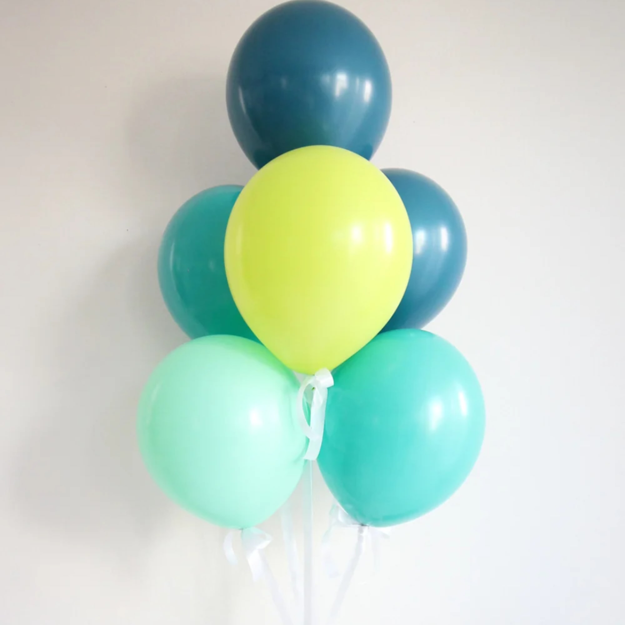 Cluster of five colorful balloons tied with white ribbon