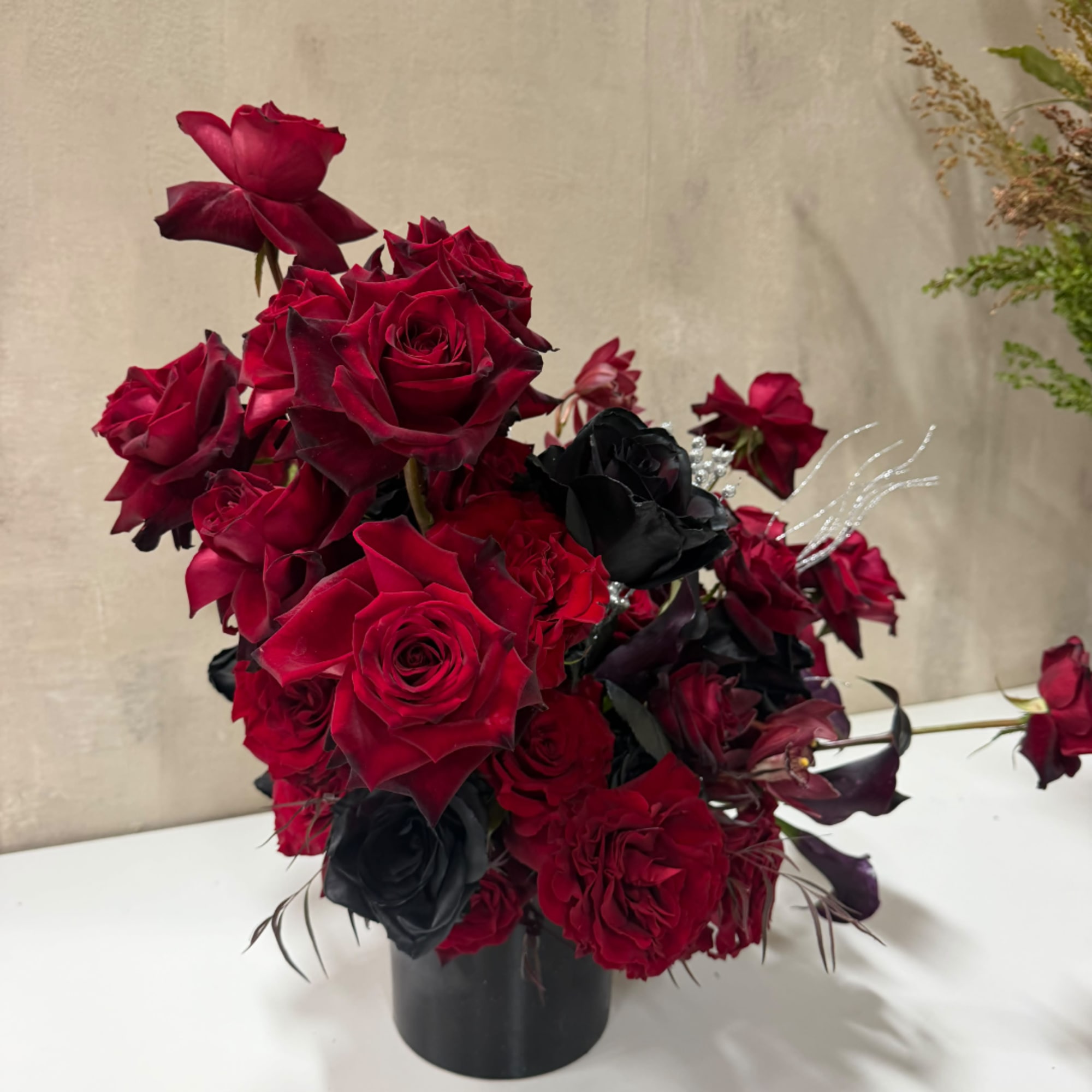 Red and black rose arrangement in a black vase
