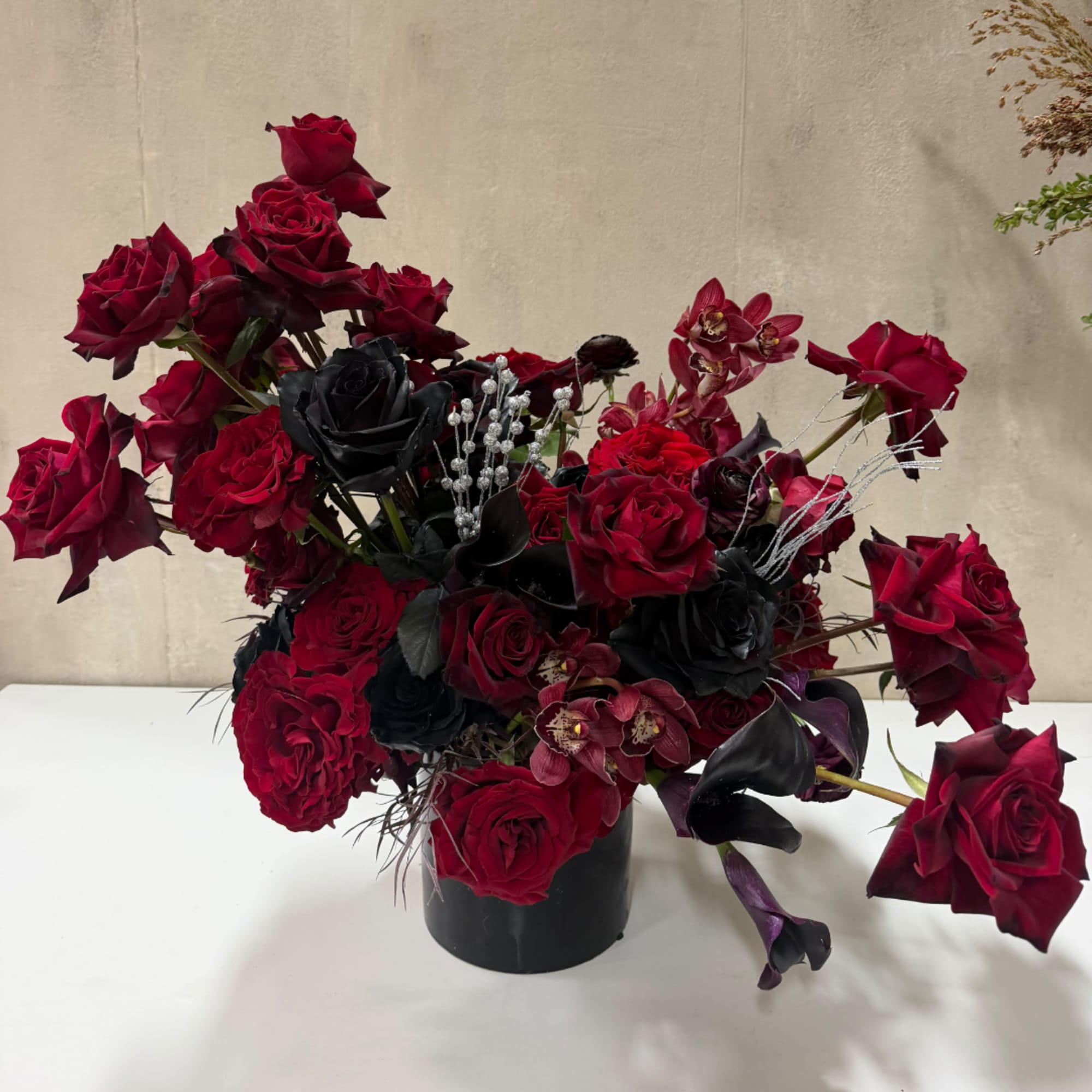 Red and black rose arrangement in a black vase