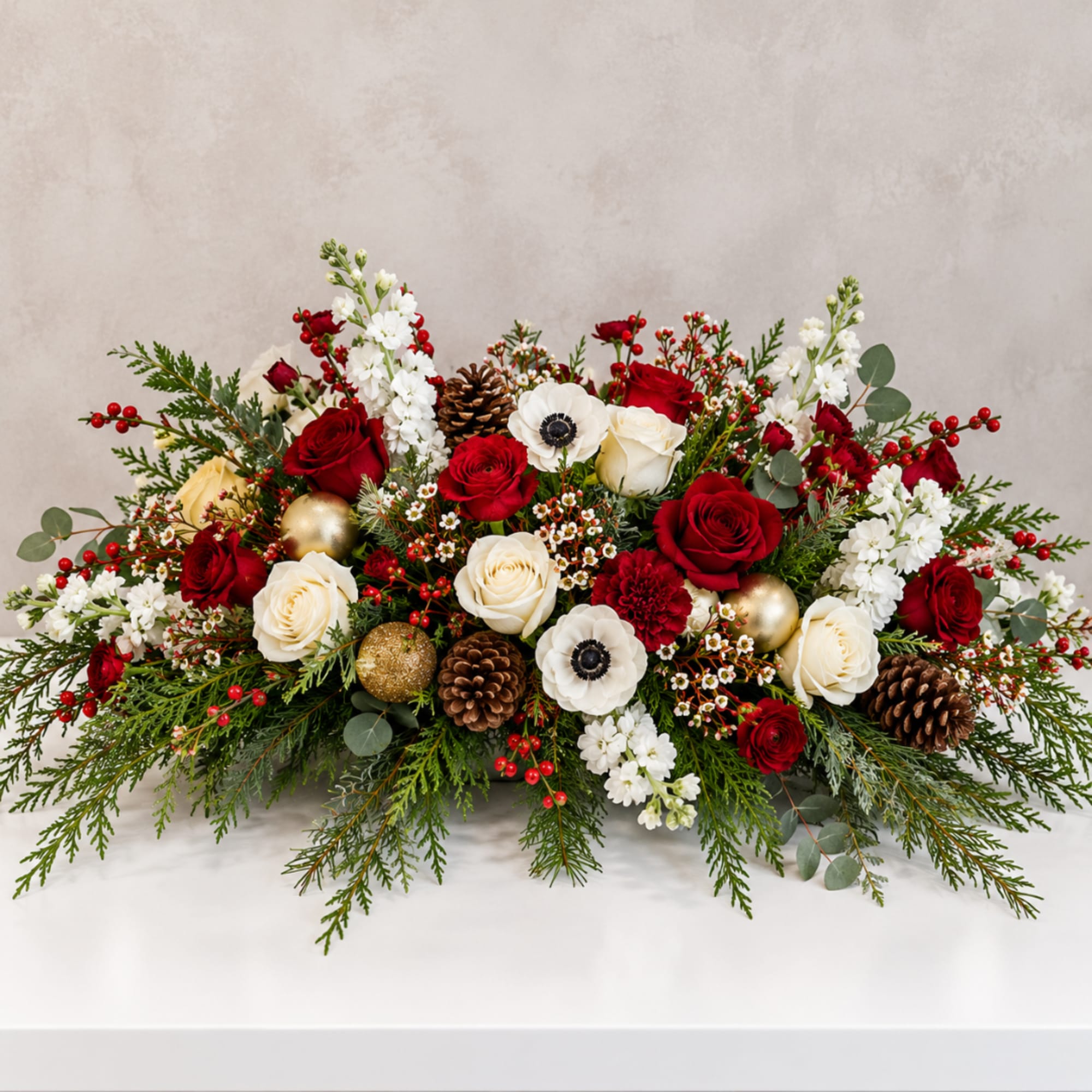 Long holiday centerpiece with red and white roses in a low arrangement