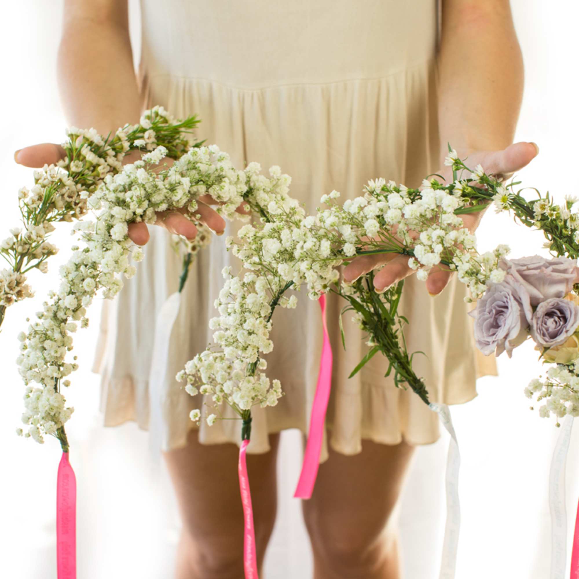 Person holding white floral garlands with small lavender roses