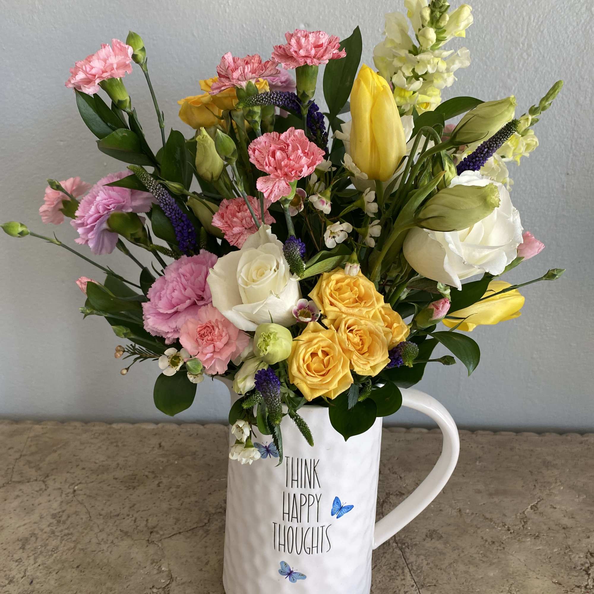 Mixed bouquet in a white mug with pink, yellow, and white flowers