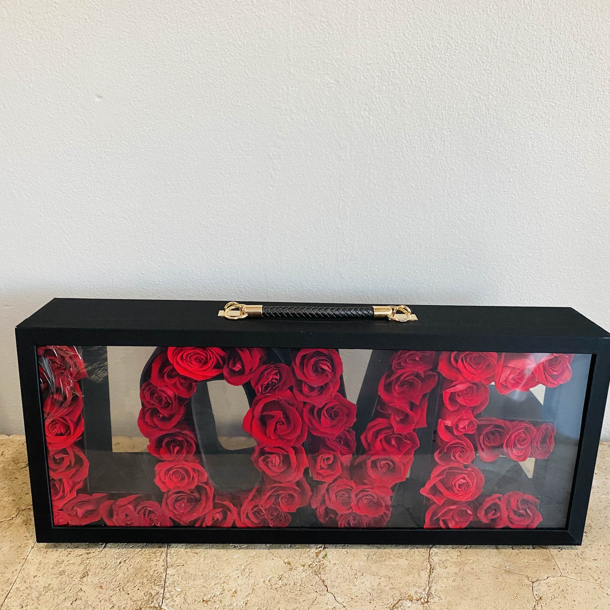 Black display case filled with red roses arranged as letters