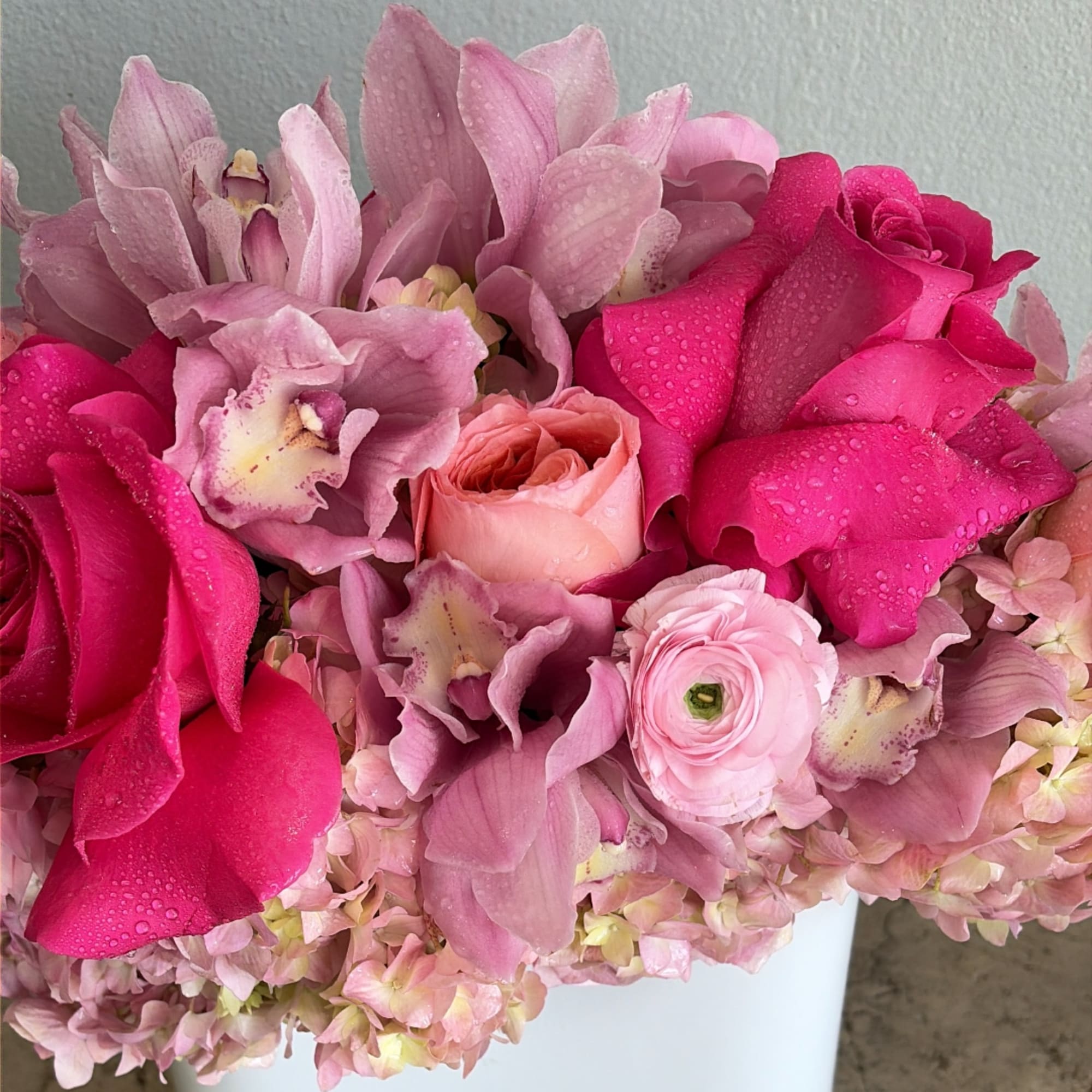 Pink bouquet with roses, orchids, and hydrangeas in a white container