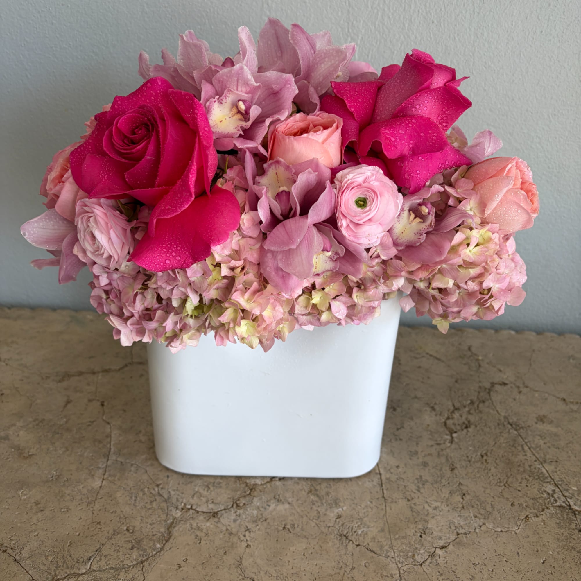 Pink and magenta flower arrangement in a white vase