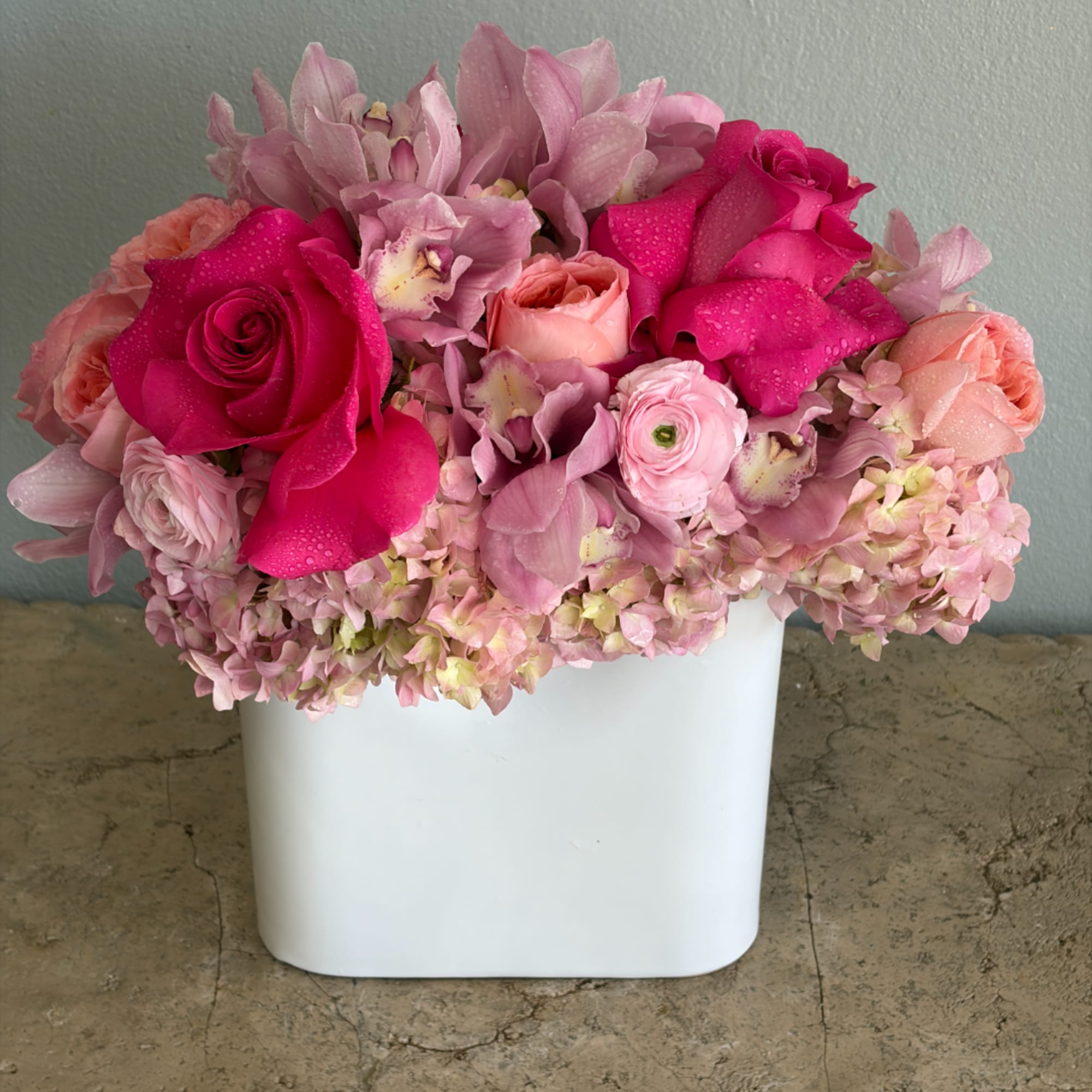 Pink roses and orchids arranged in a white vase