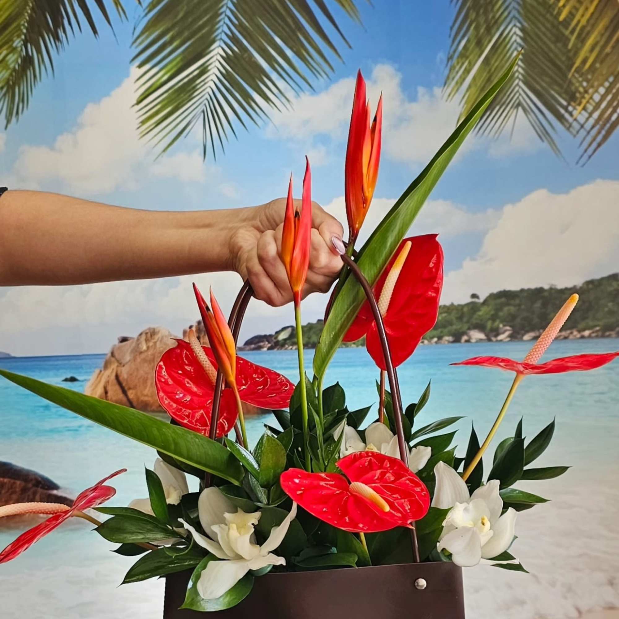 Tropical floral arrangement with red anthuriums and white orchids in a brown box
