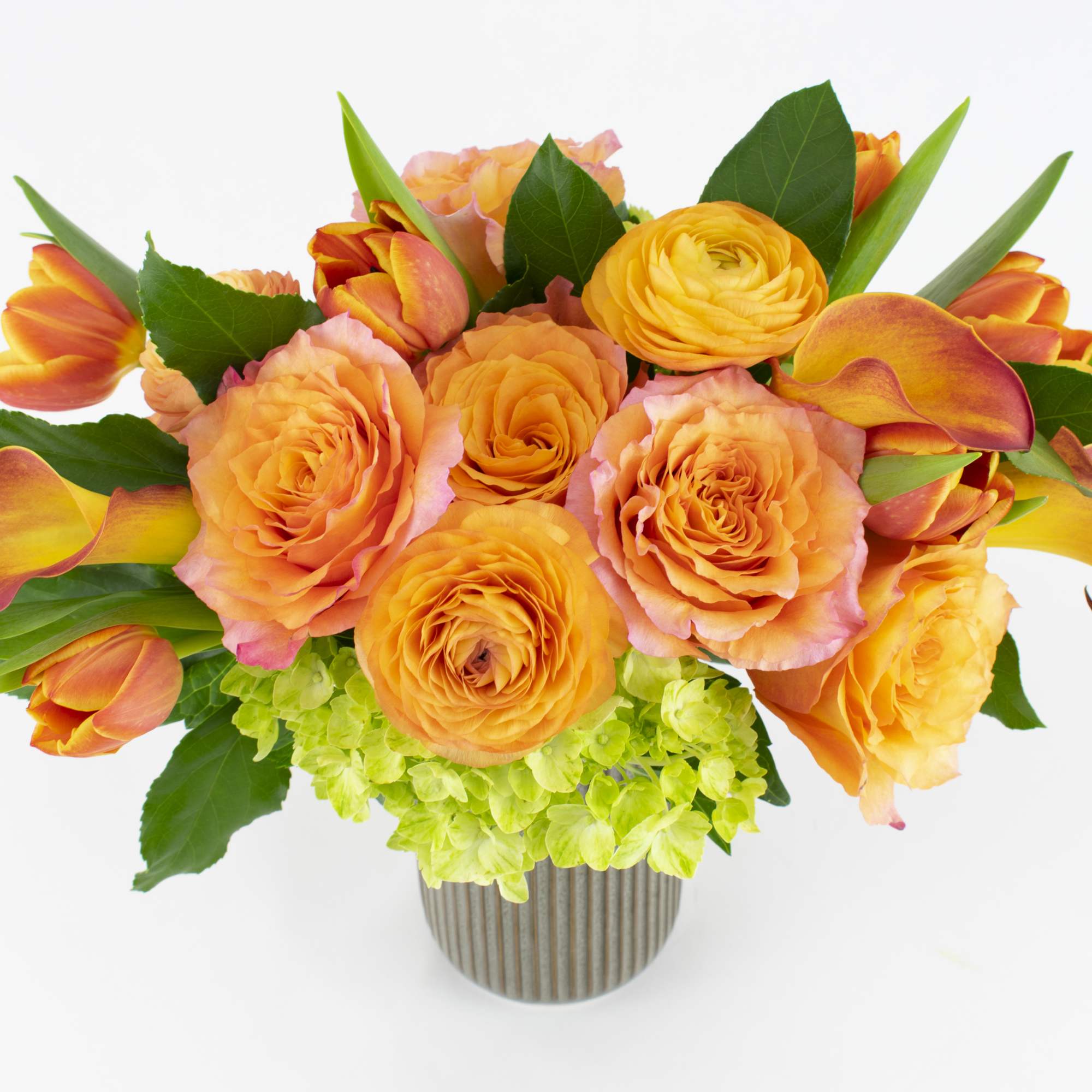 Orange roses and tulips in a striped vase with green hydrangea