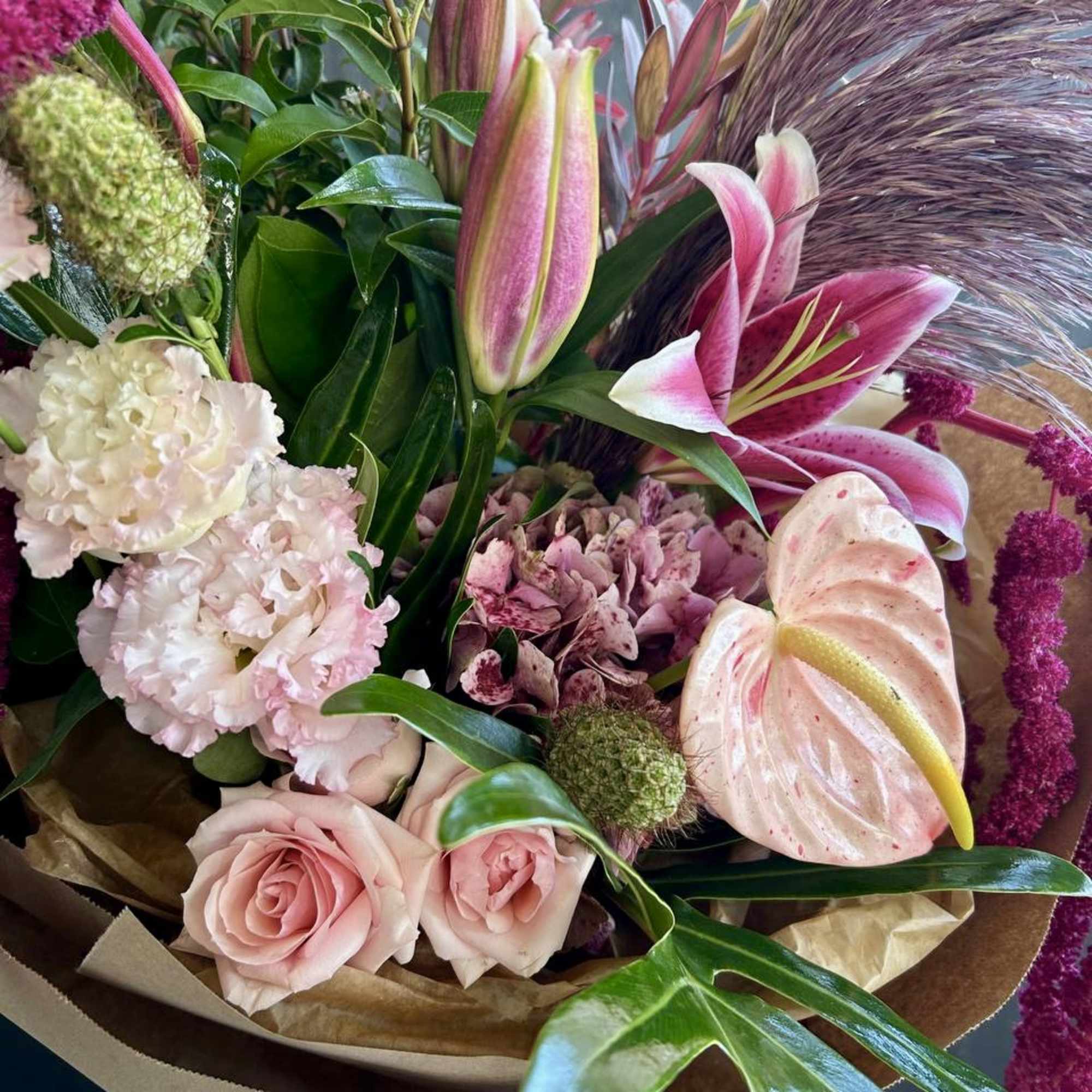 Bouquet of pink lilies, roses, and carnations with green accents
