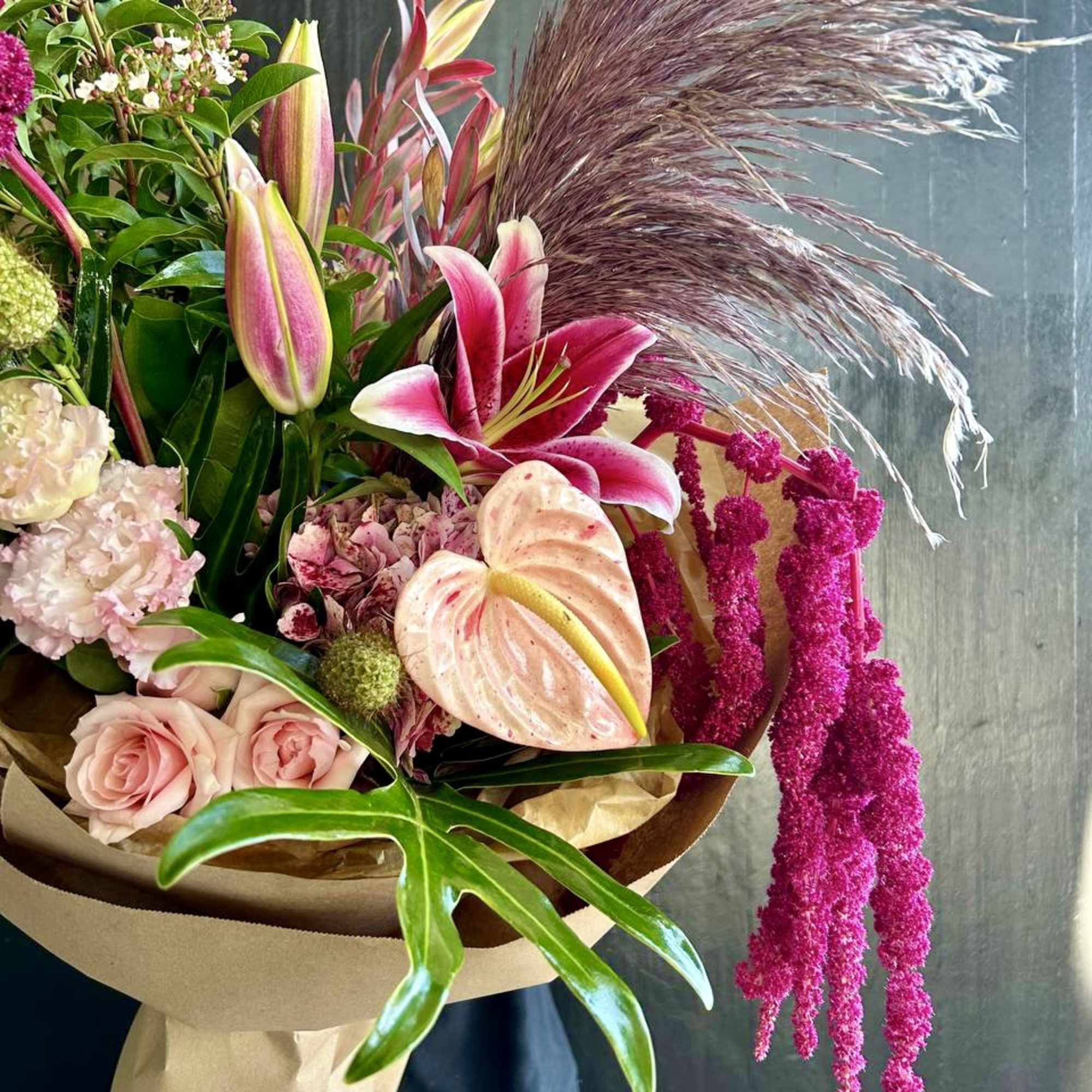 Bouquet with pink lilies, roses, and anthurium in kraft paper