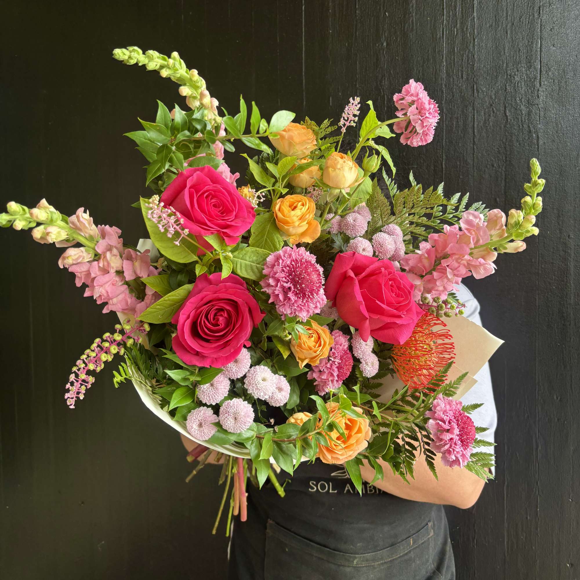 Handheld bouquet of pink, orange, and yellow flowers