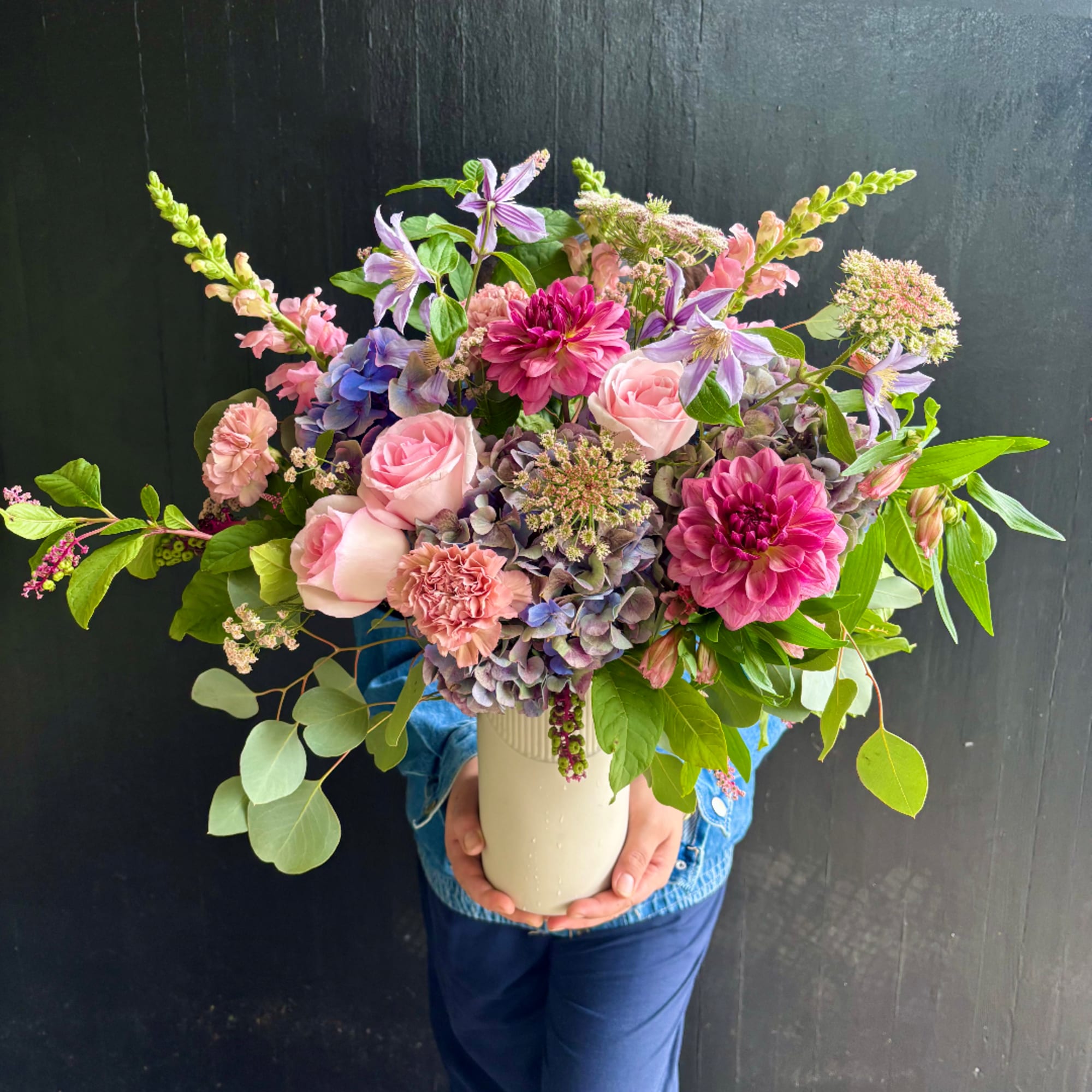 Mixed pink and purple flower arrangement in a white vase
