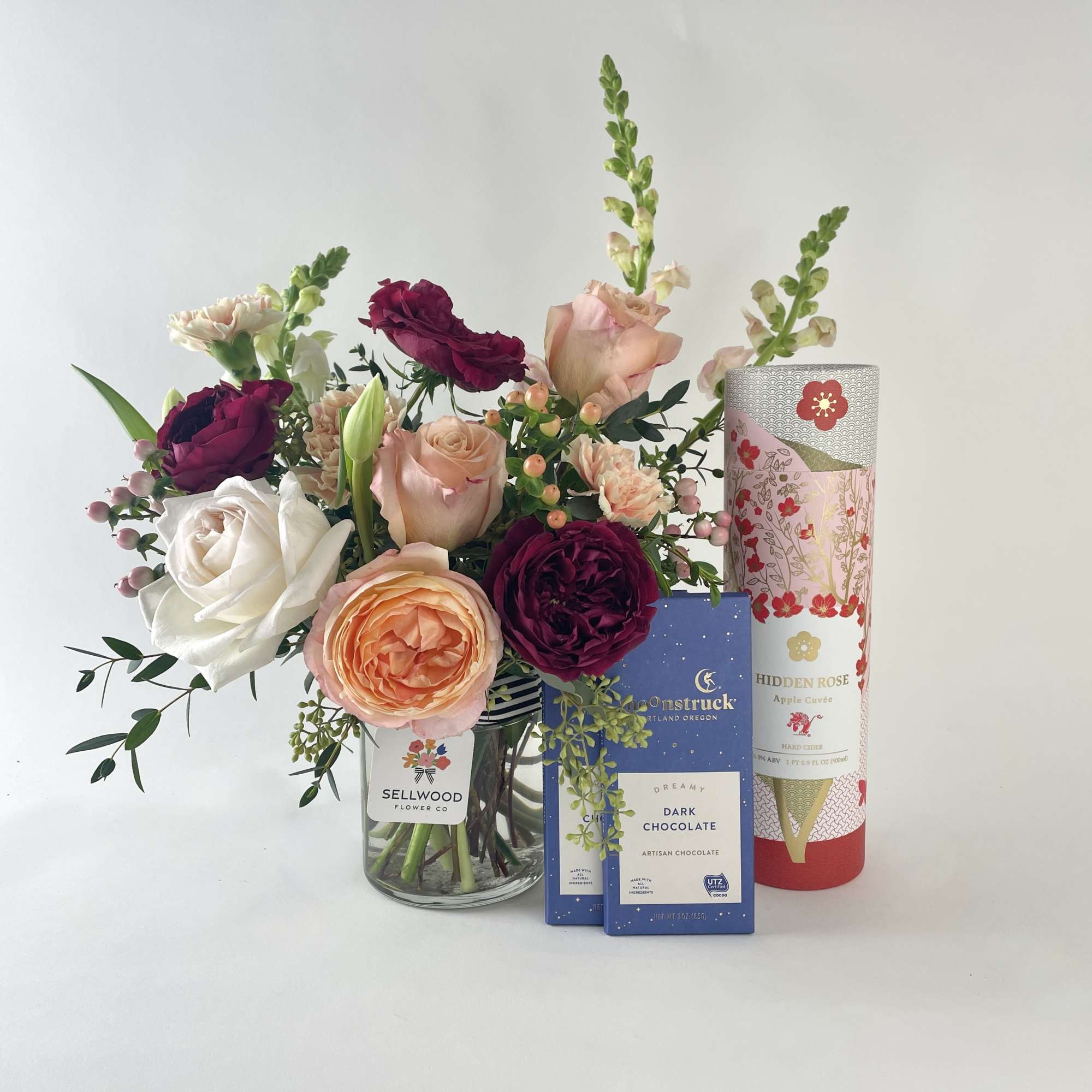 Mixed roses in a glass vase with chocolate and a tall gift tube
