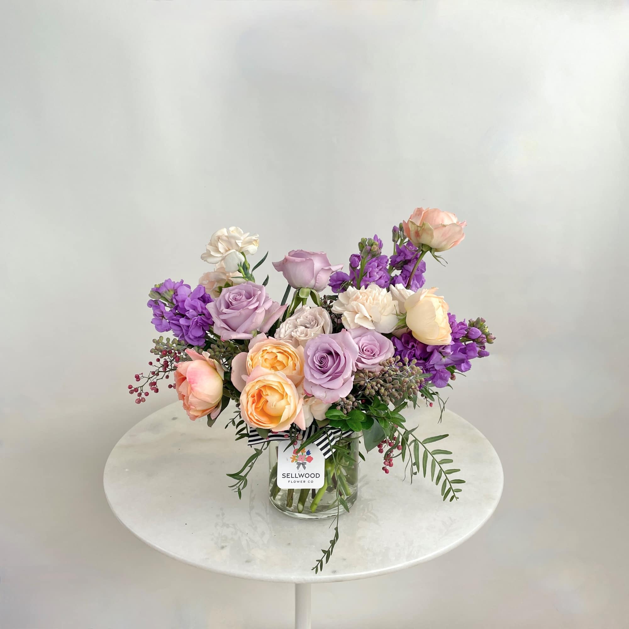 Bouquet of pastel roses and purple flowers in a glass vase